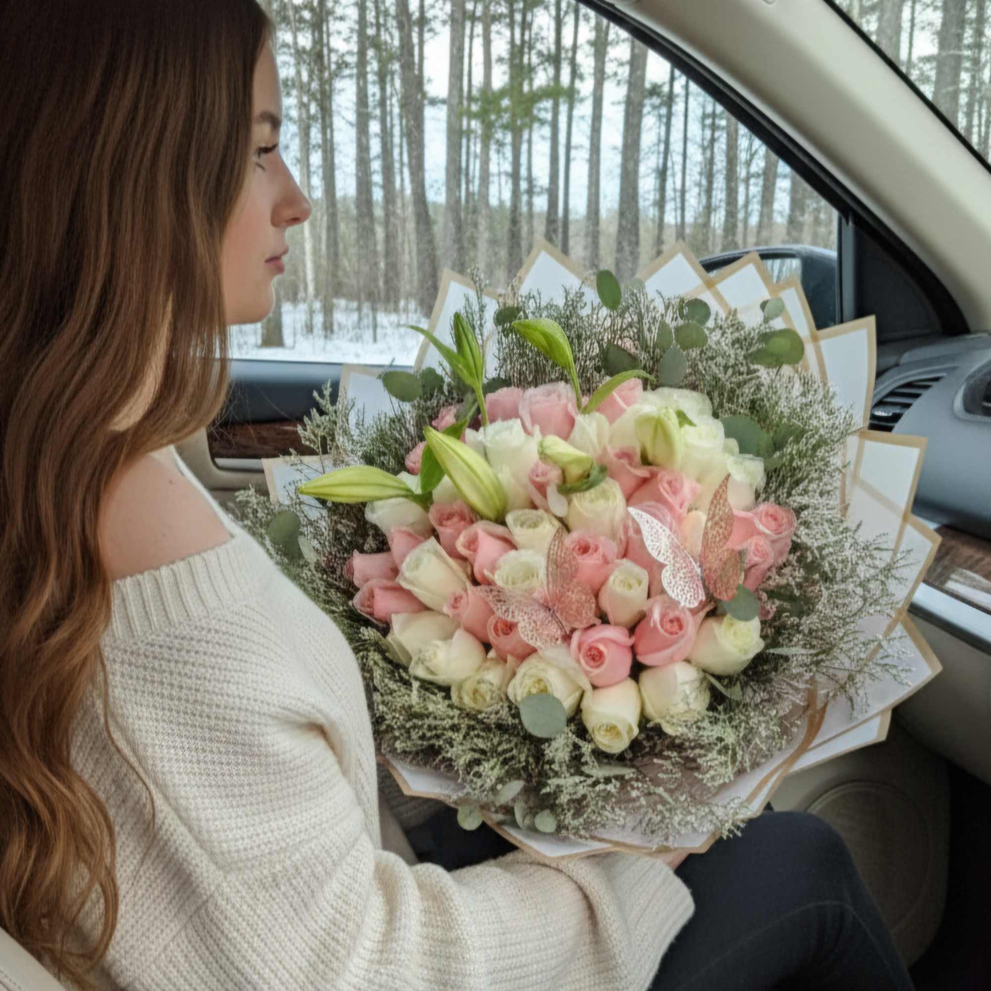 Woman holding a bouquet of pink and white roses in a car