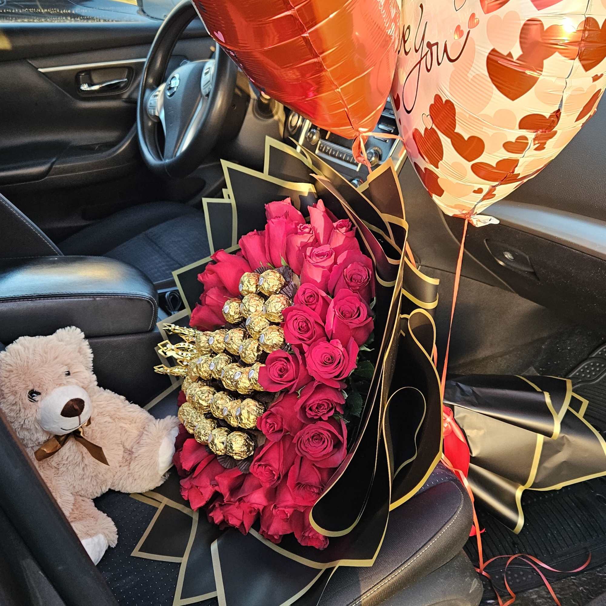Bouquet of hot pink roses with heart balloons and a teddy bear in a car seat