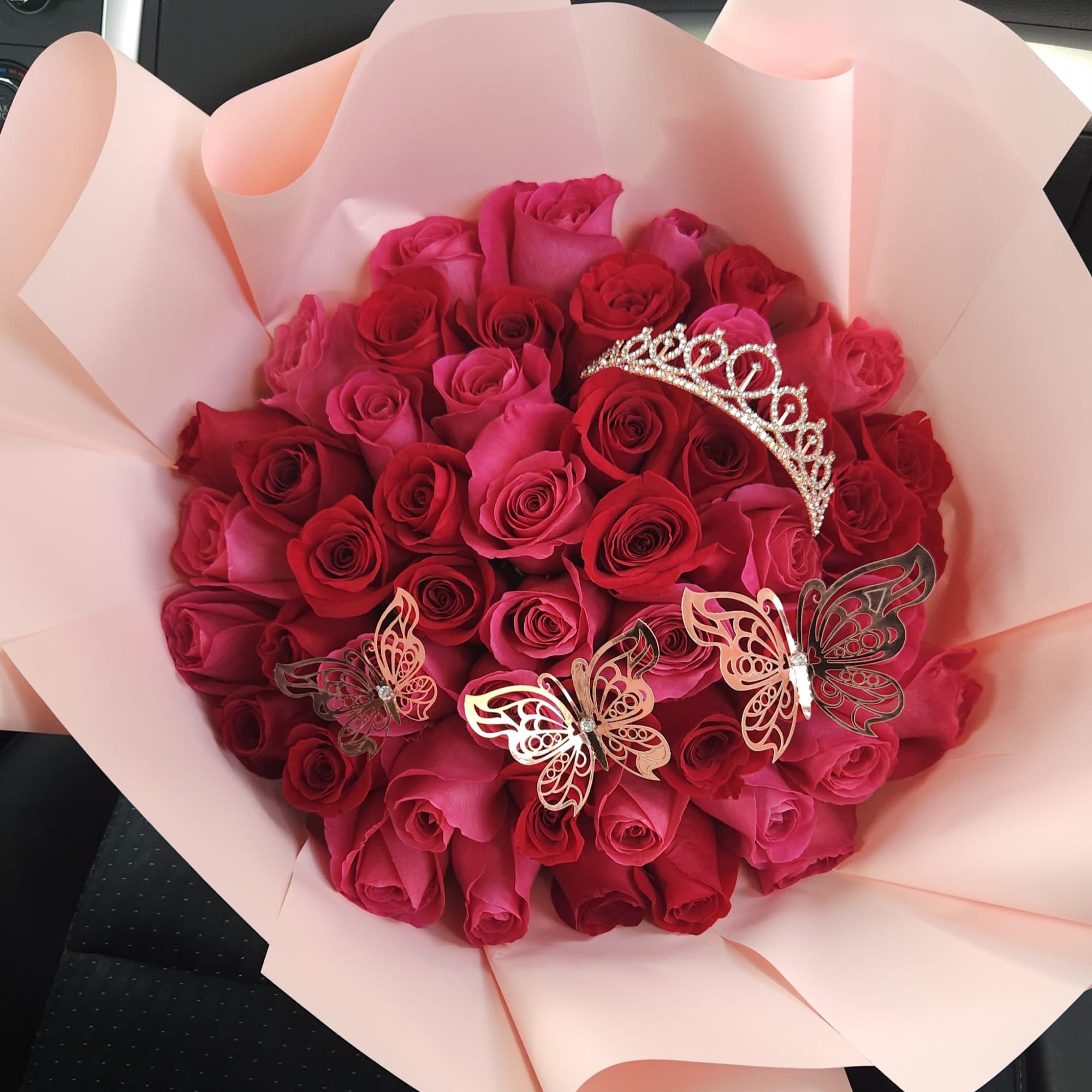 Bouquet of pink and red roses with butterfly decorations and a tiara