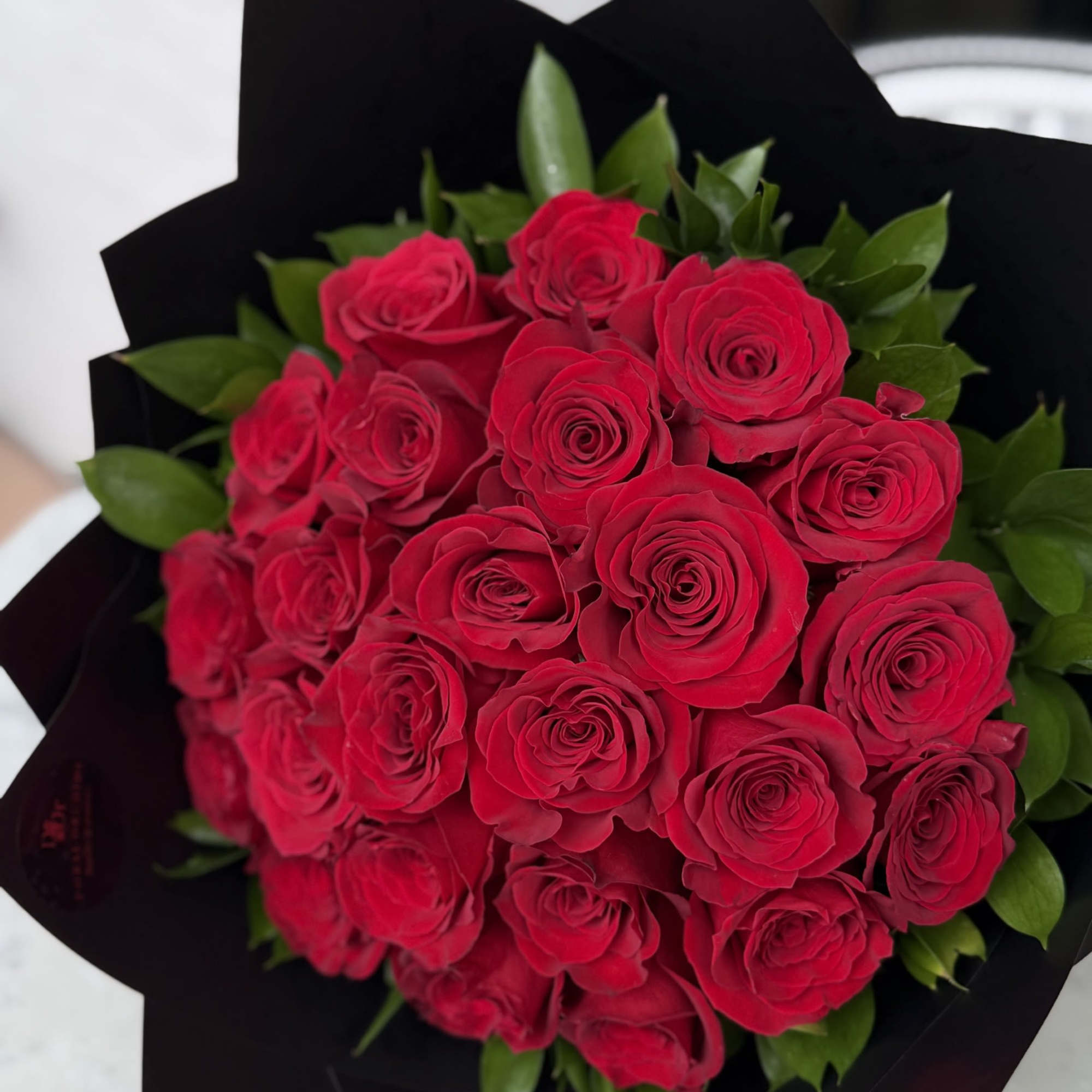 A dramatic bouquet of 24 velvety red roses wrapped in sleek black