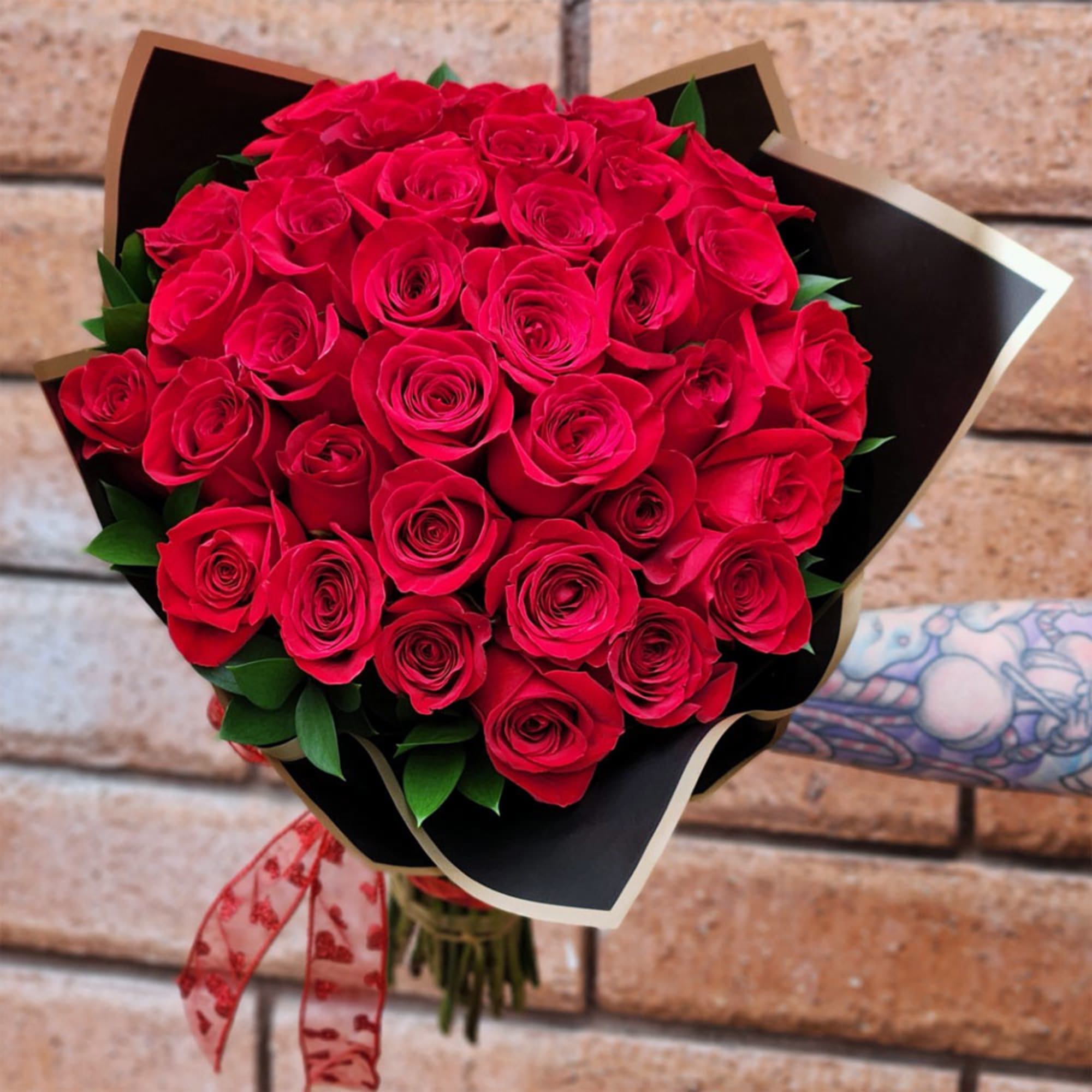 Bouquet of red roses wrapped in black paper with a red ribbon