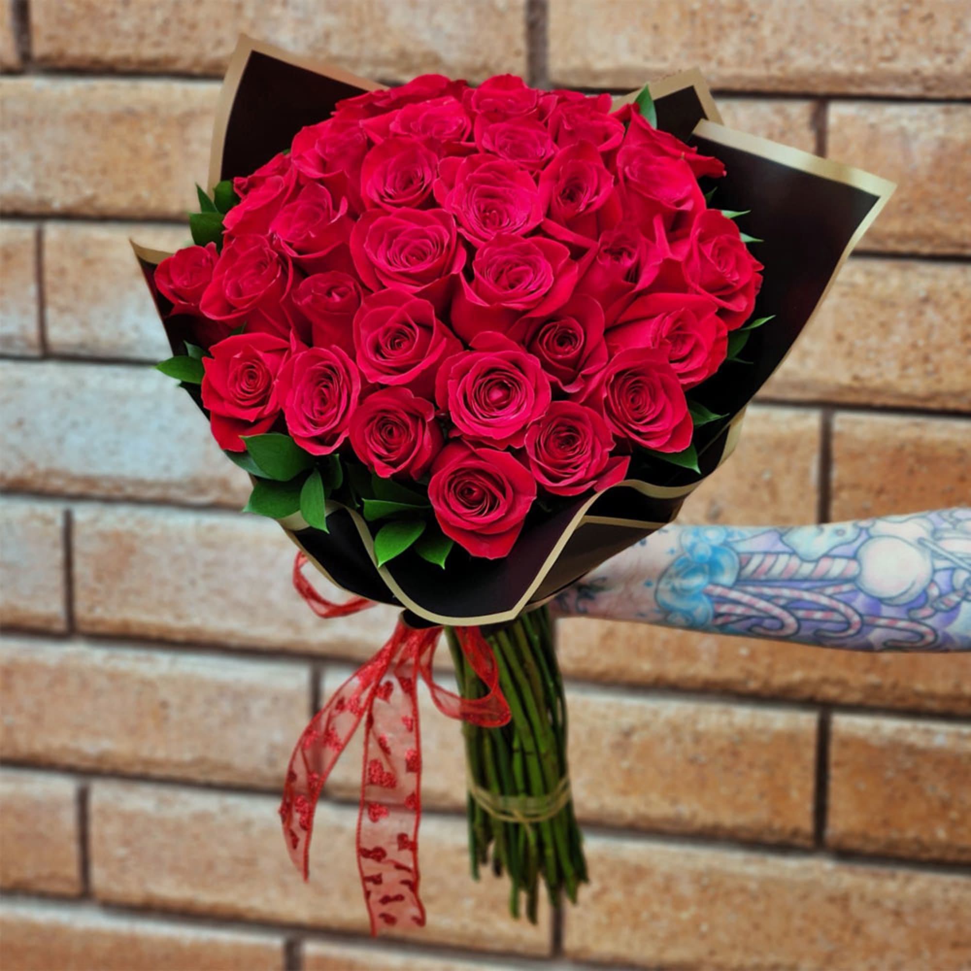Bouquet of red roses wrapped in black paper with a red ribbon