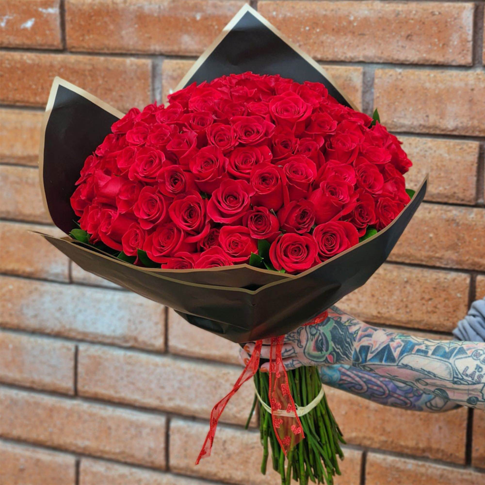 Large bouquet of red roses wrapped in black paper