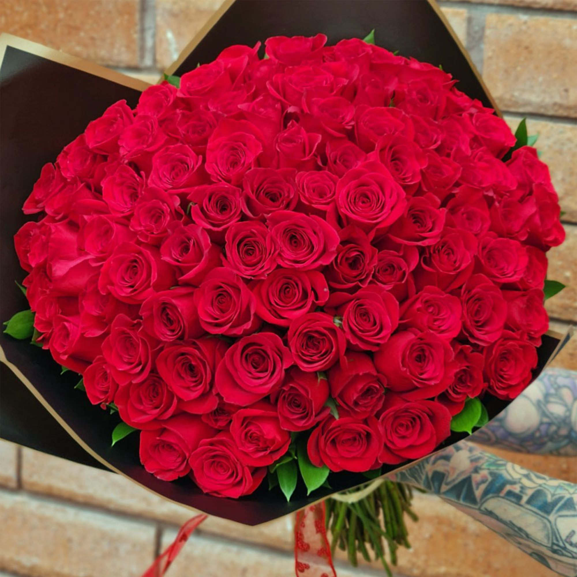 Large bouquet of red roses wrapped in black paper
