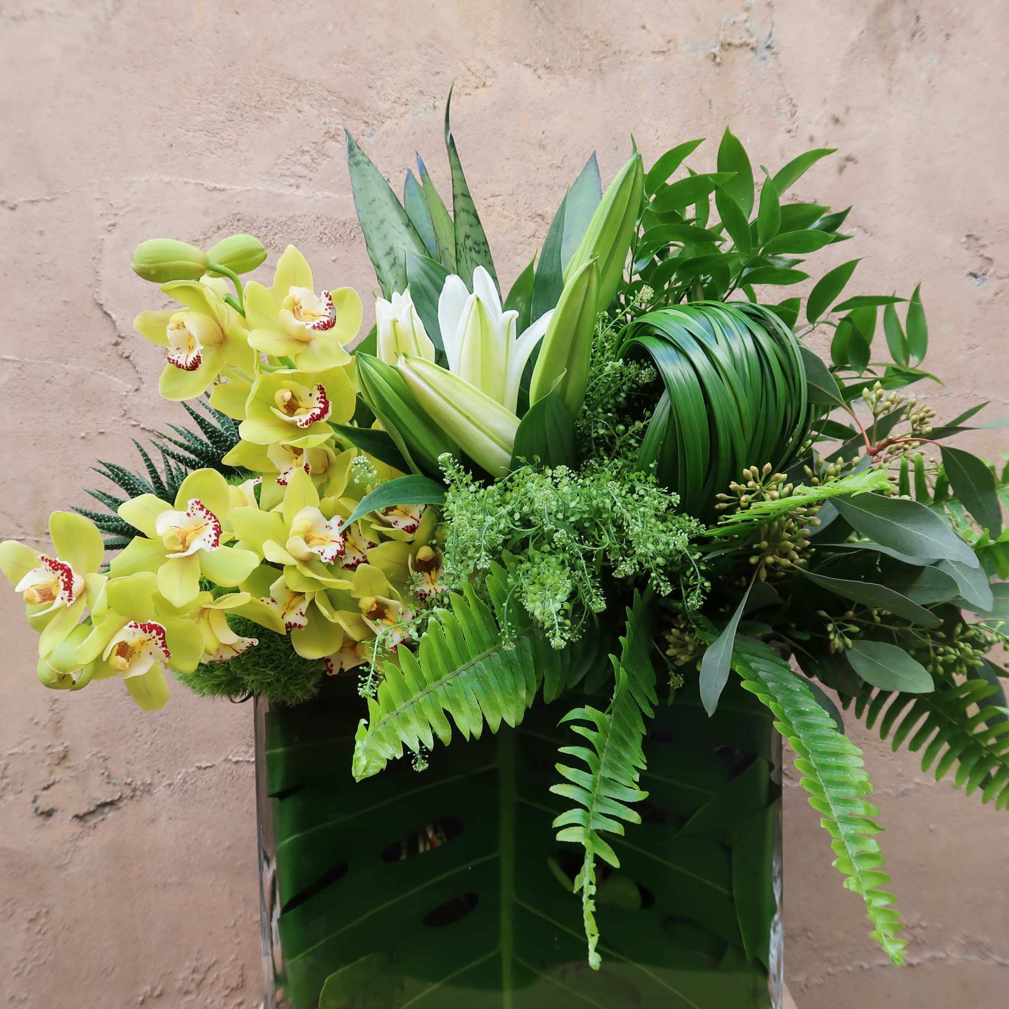 An elegant arrangement of greens, orchids and Lillies, perfect for all occasions.