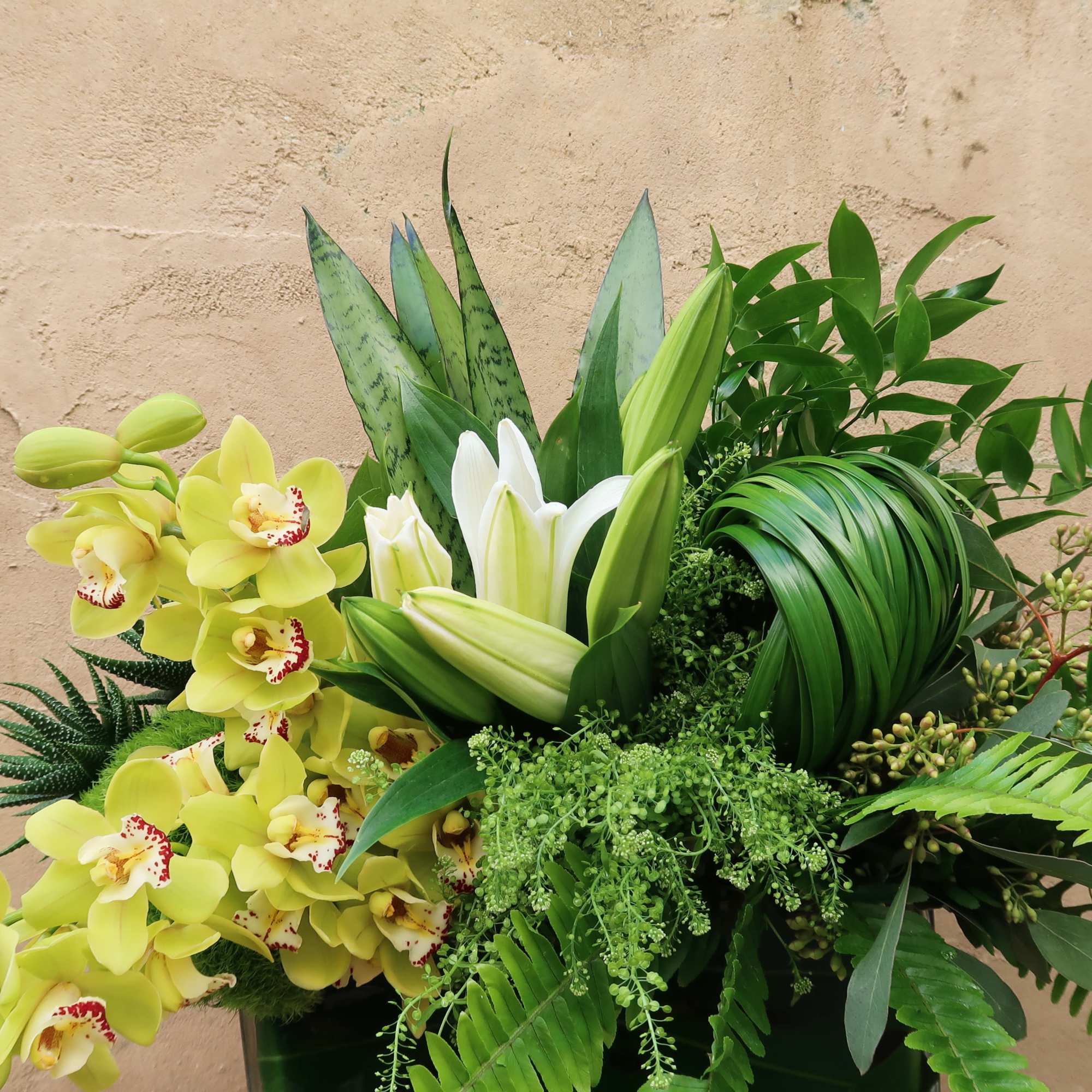 An elegant arrangement of greens, orchids and Lillies, perfect for all occasions.
