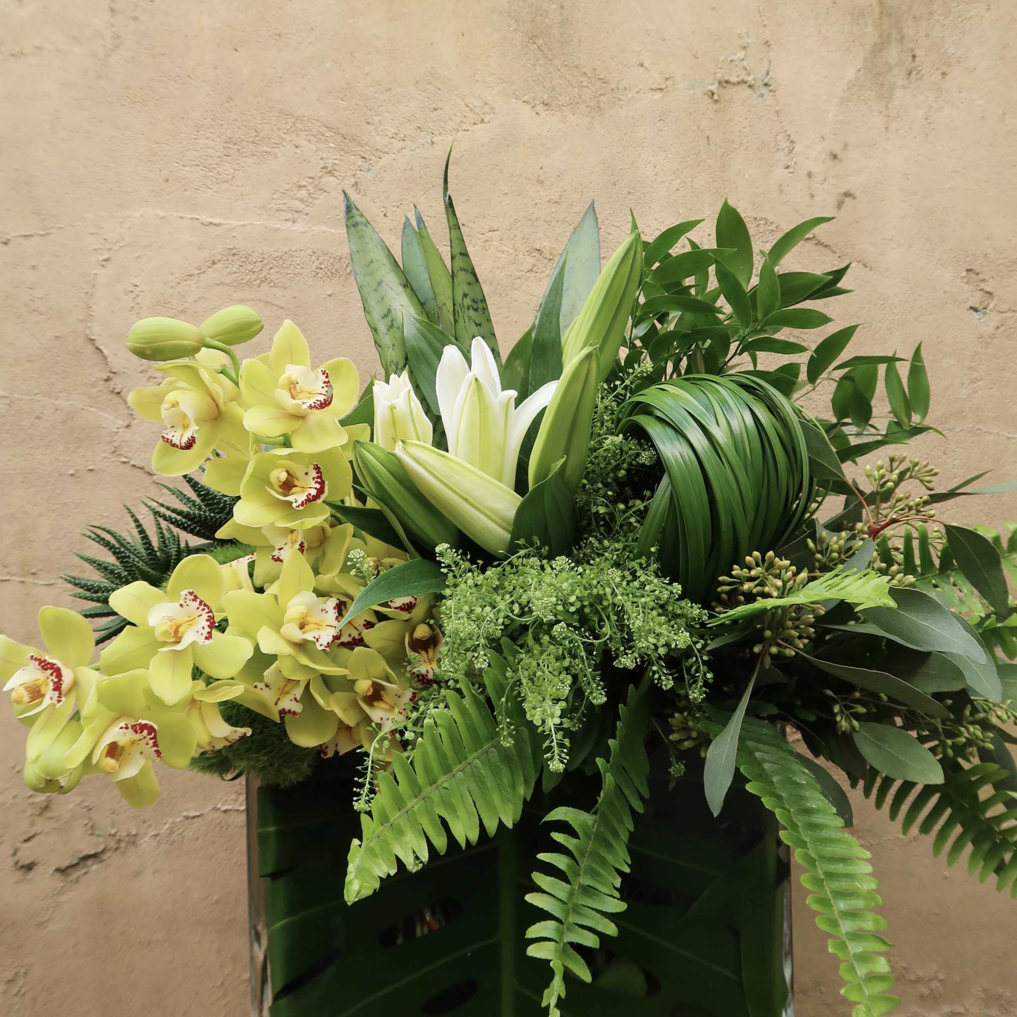 An elegant arrangement of greens, orchids and Lillies, perfect for all occasions.