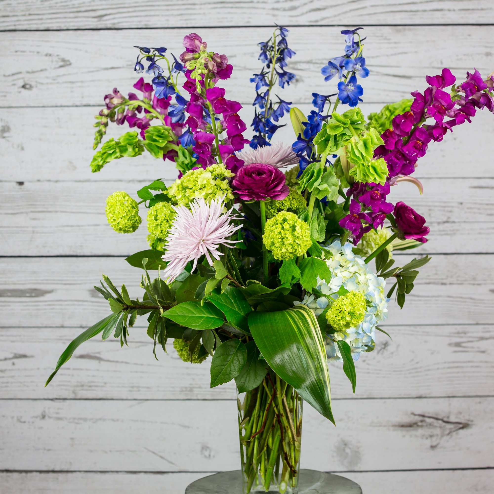Colorful bouquet in a clear glass vase with purple, blue, and green flowers
