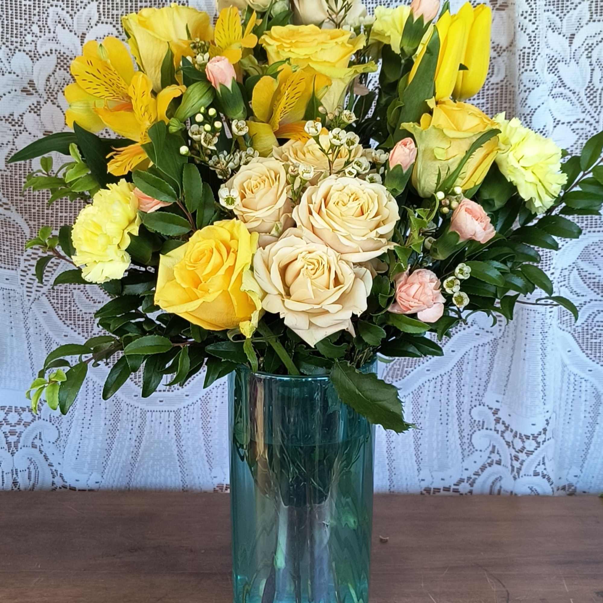 Yellow and cream roses arranged in a blue glass vase