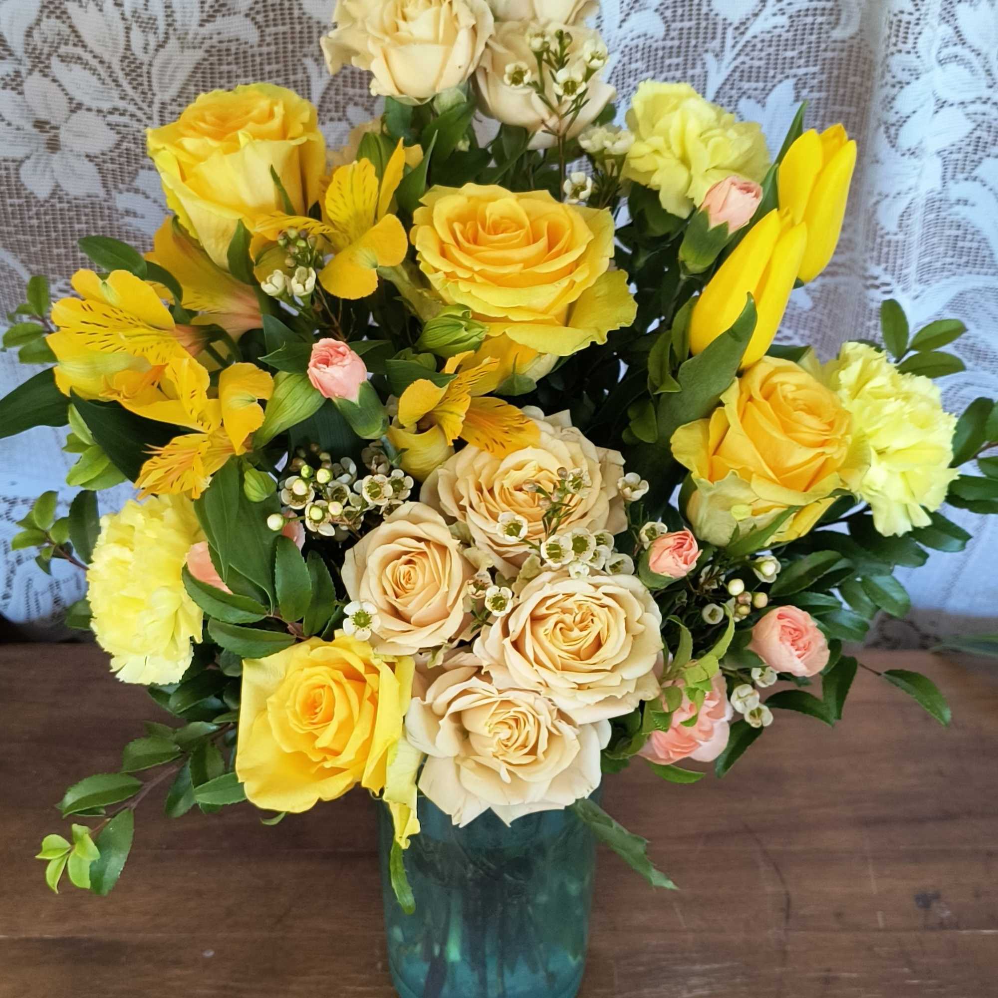 Yellow and cream roses arranged in a blue glass vase