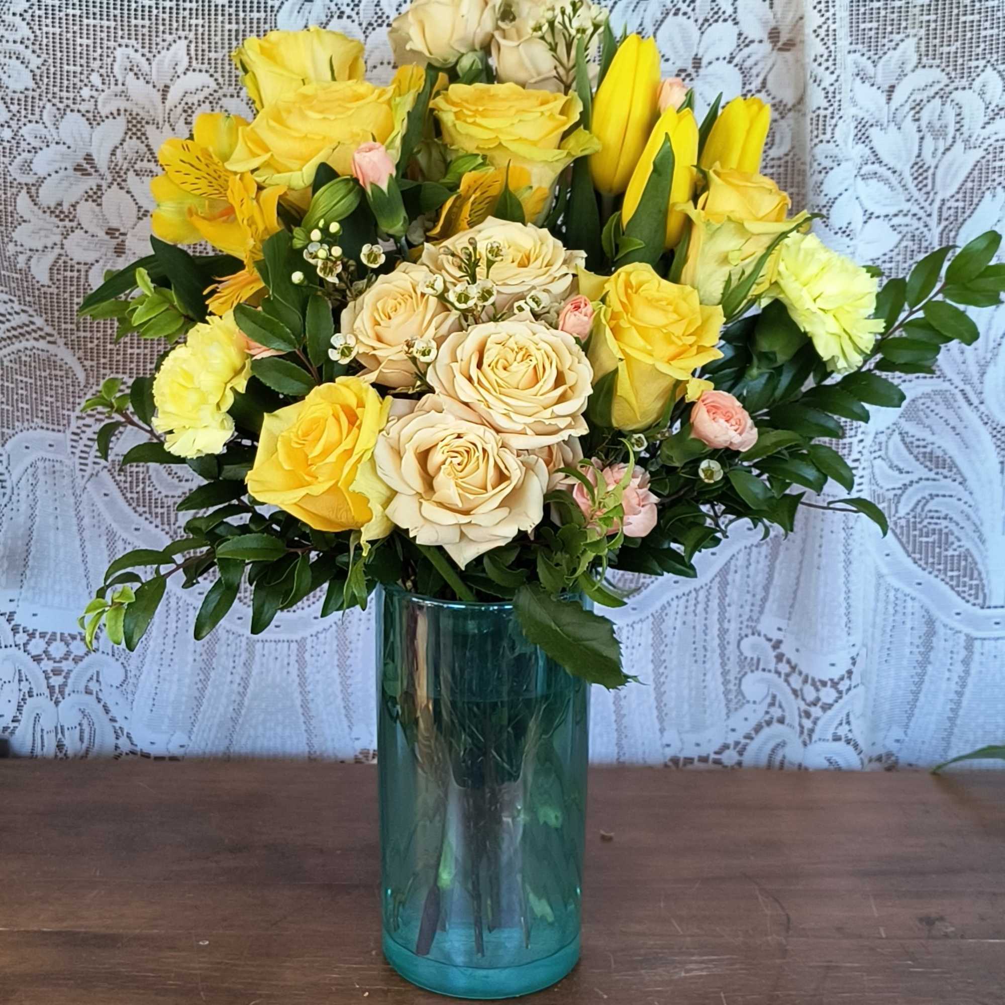 Yellow and cream roses arranged in a blue glass vase