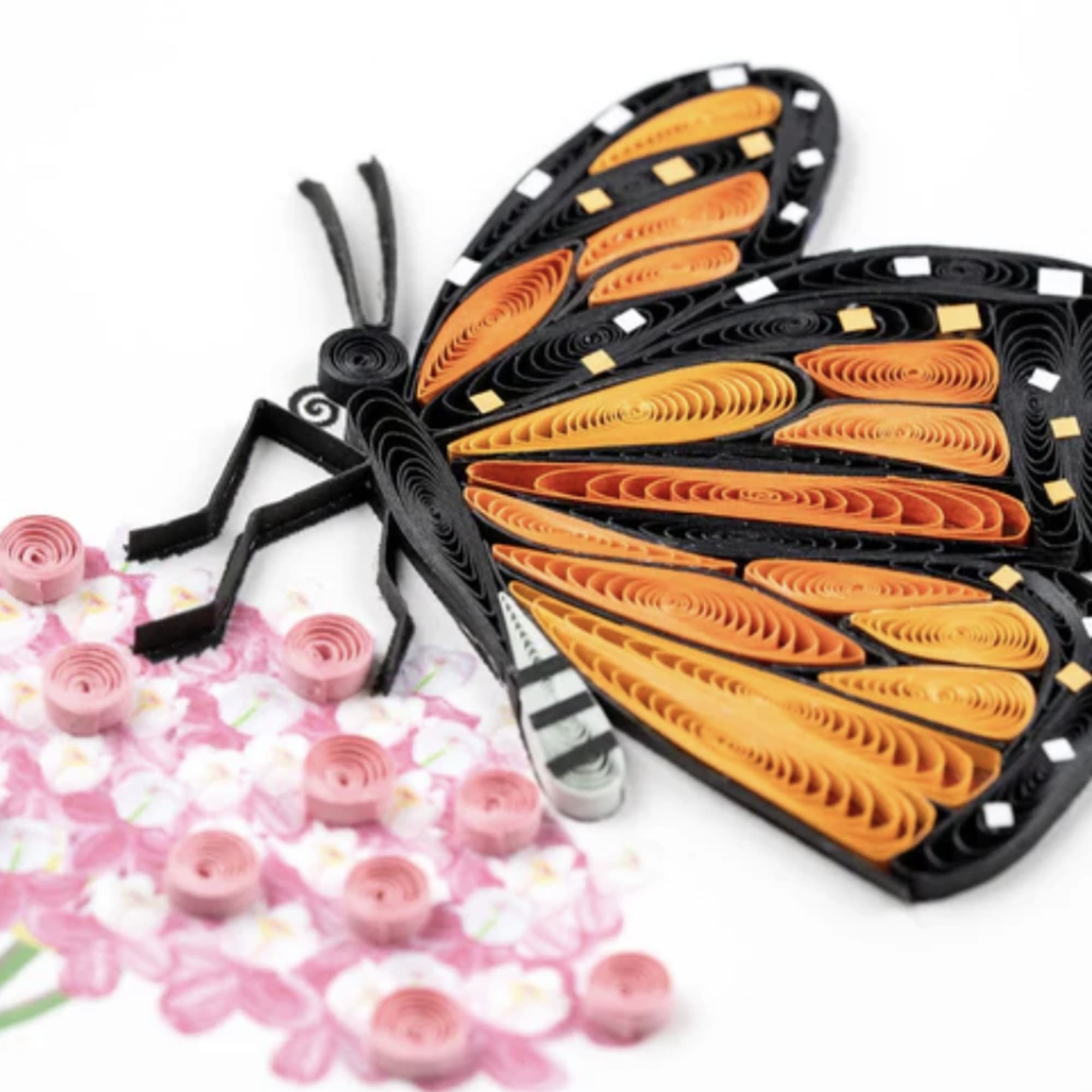 Quilled orange and black butterfly on a card with pink floral accents