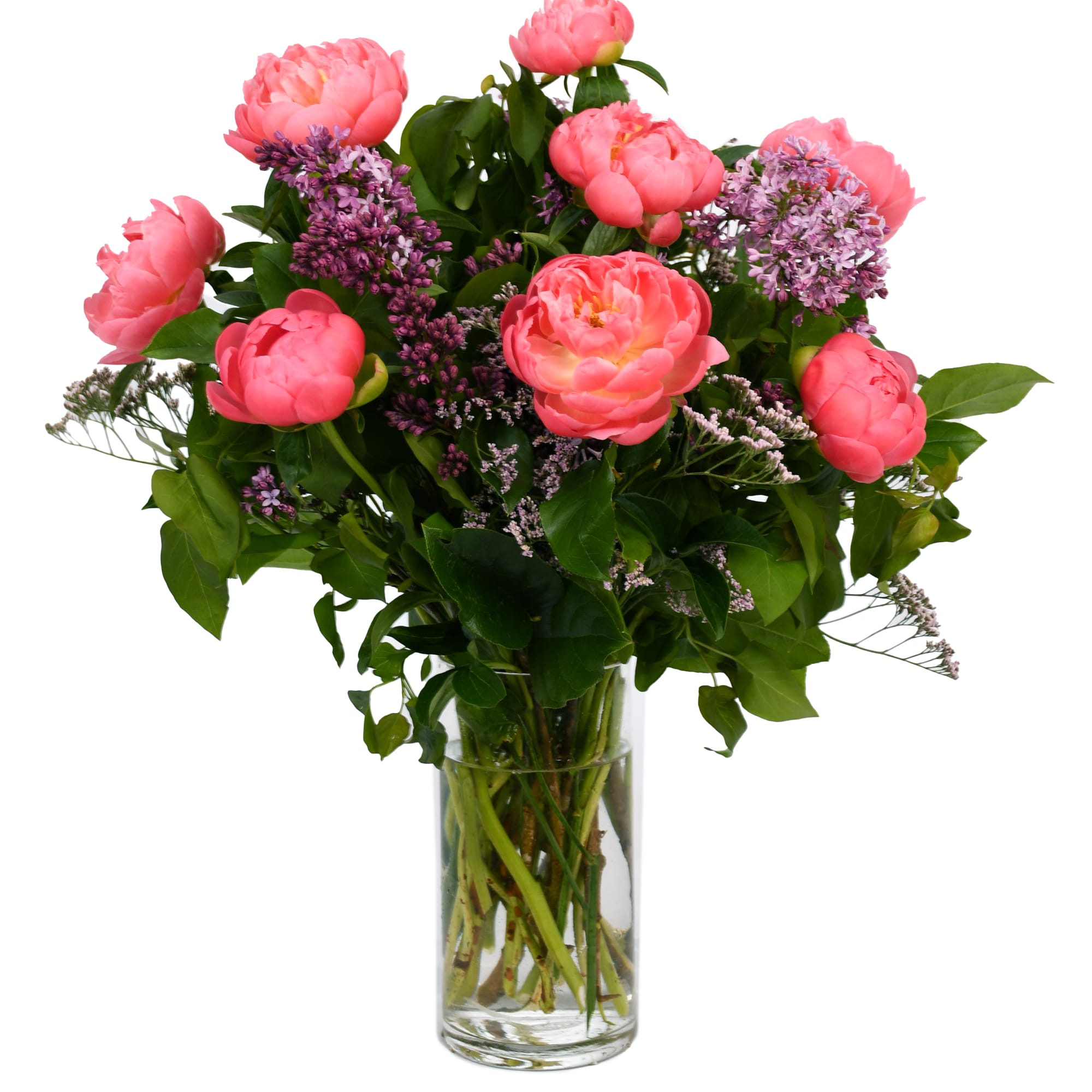 Pink peonies and purple filler flowers in a clear glass vase