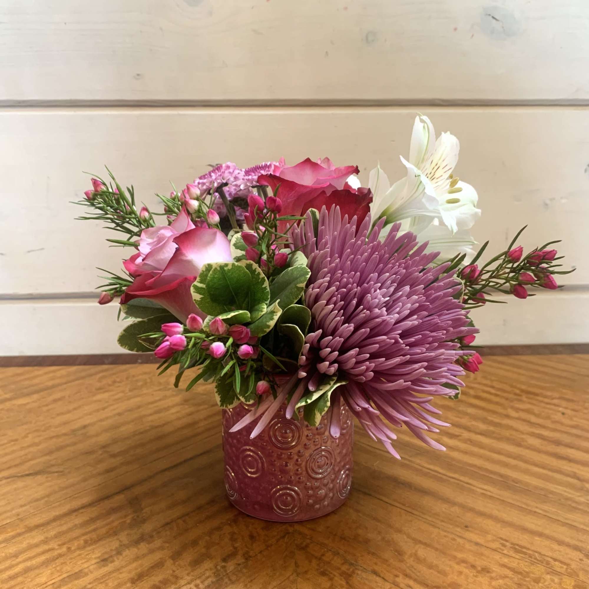 A petite arrangement of lavender roses with lavender chrysanthemums in a petite