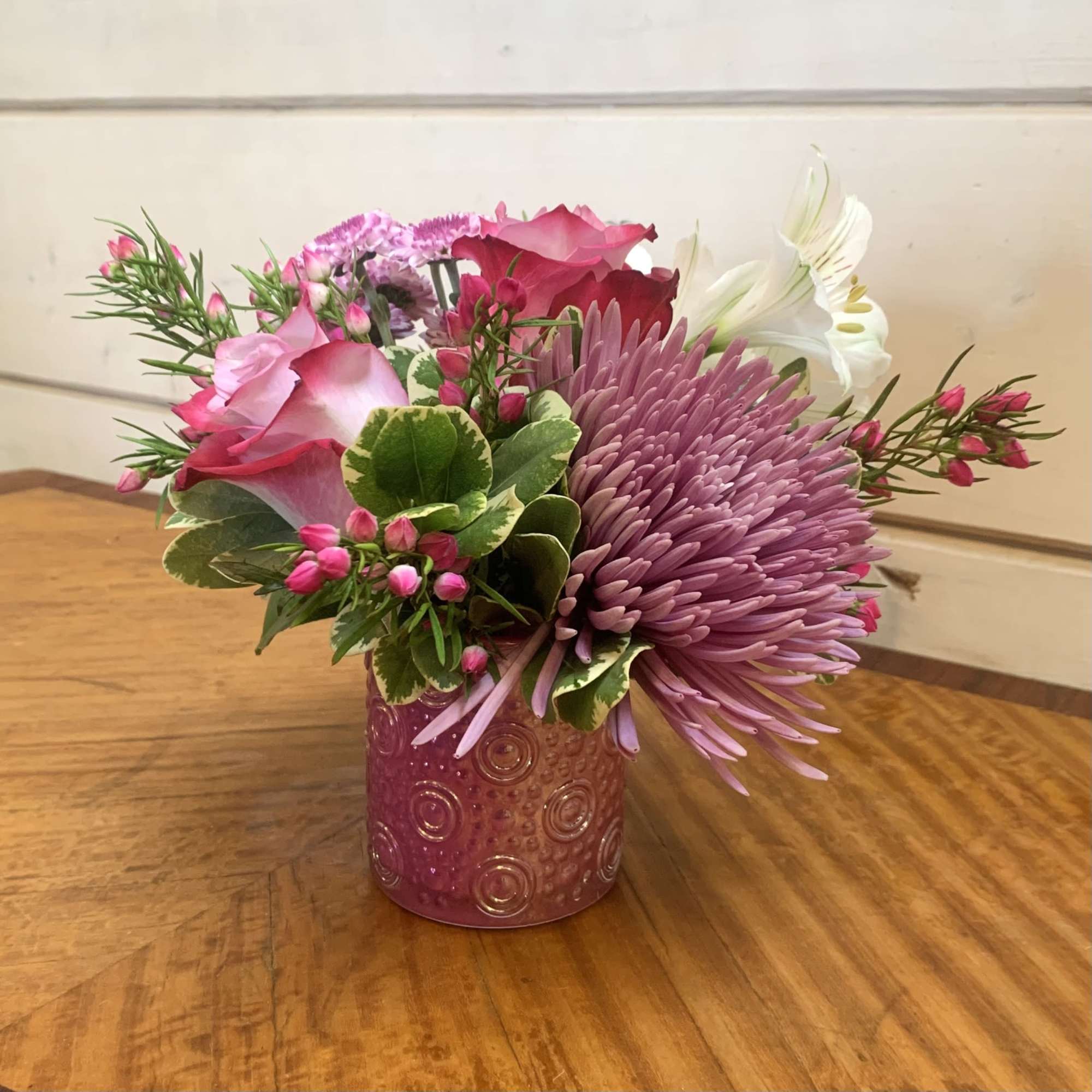 A petite arrangement of lavender roses with lavender chrysanthemums in a petite