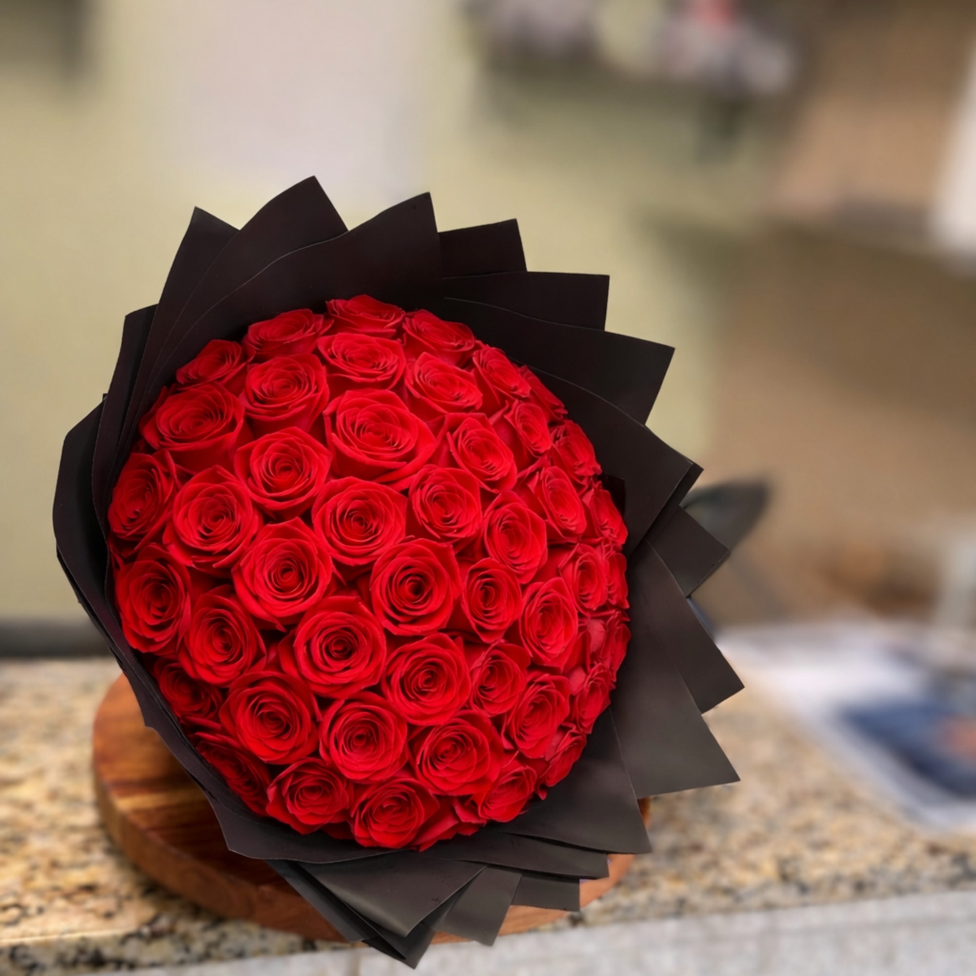 Round bouquet of red roses wrapped in black paper