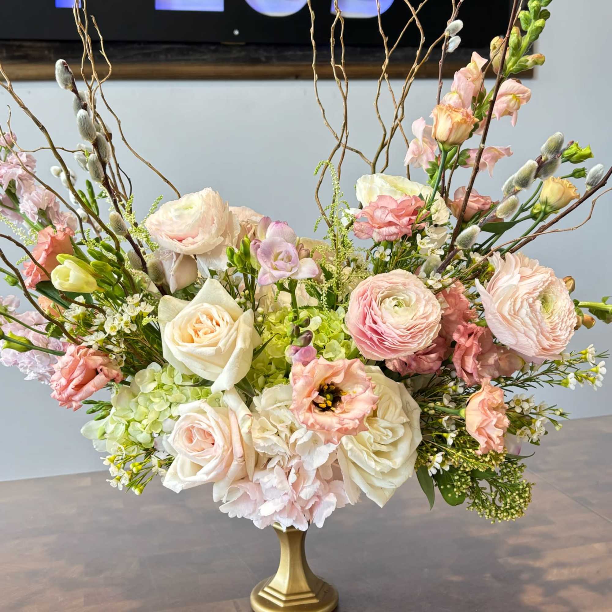 Pastel floral arrangement in a gold pedestal vase