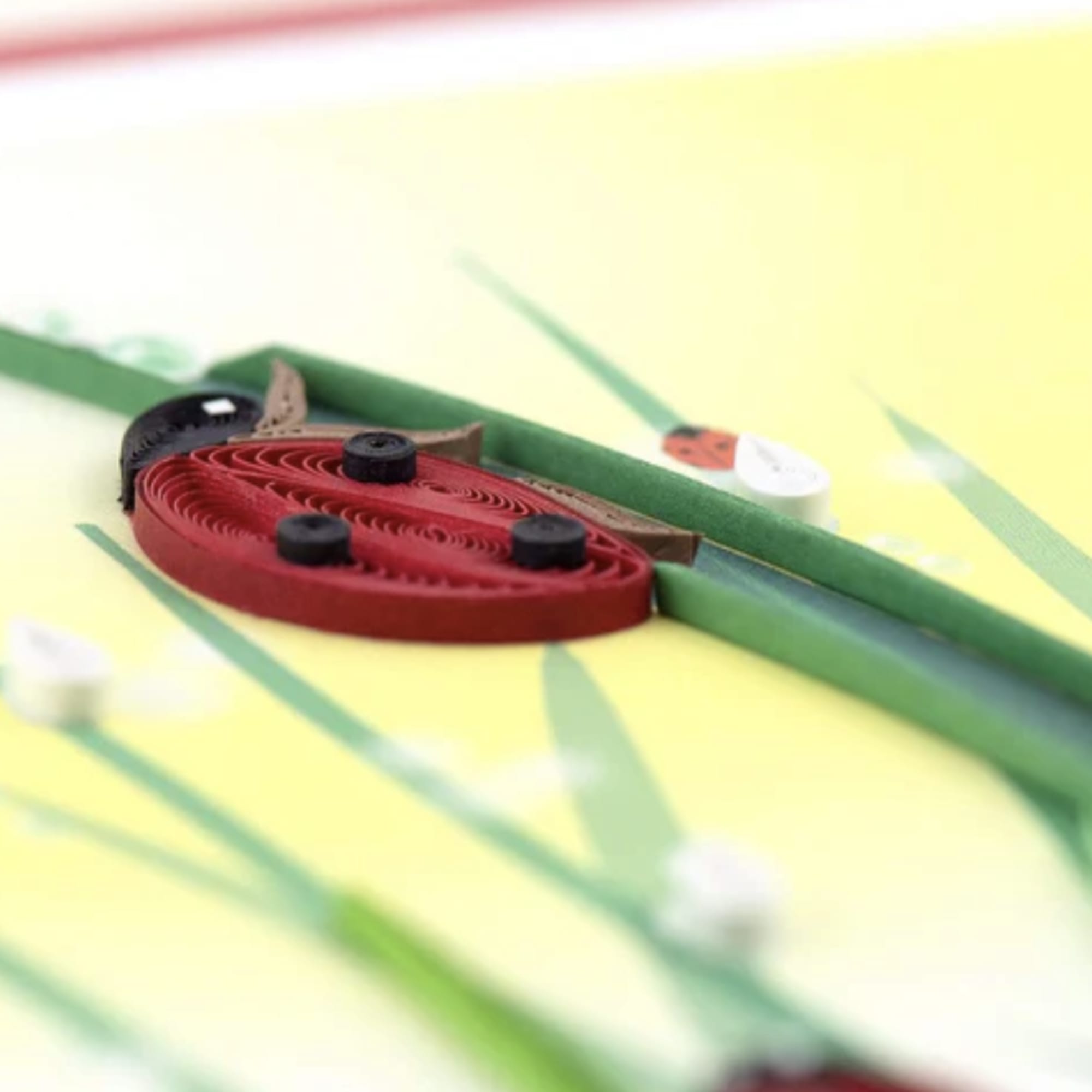 Paper quilled ladybug on a yellow floral background