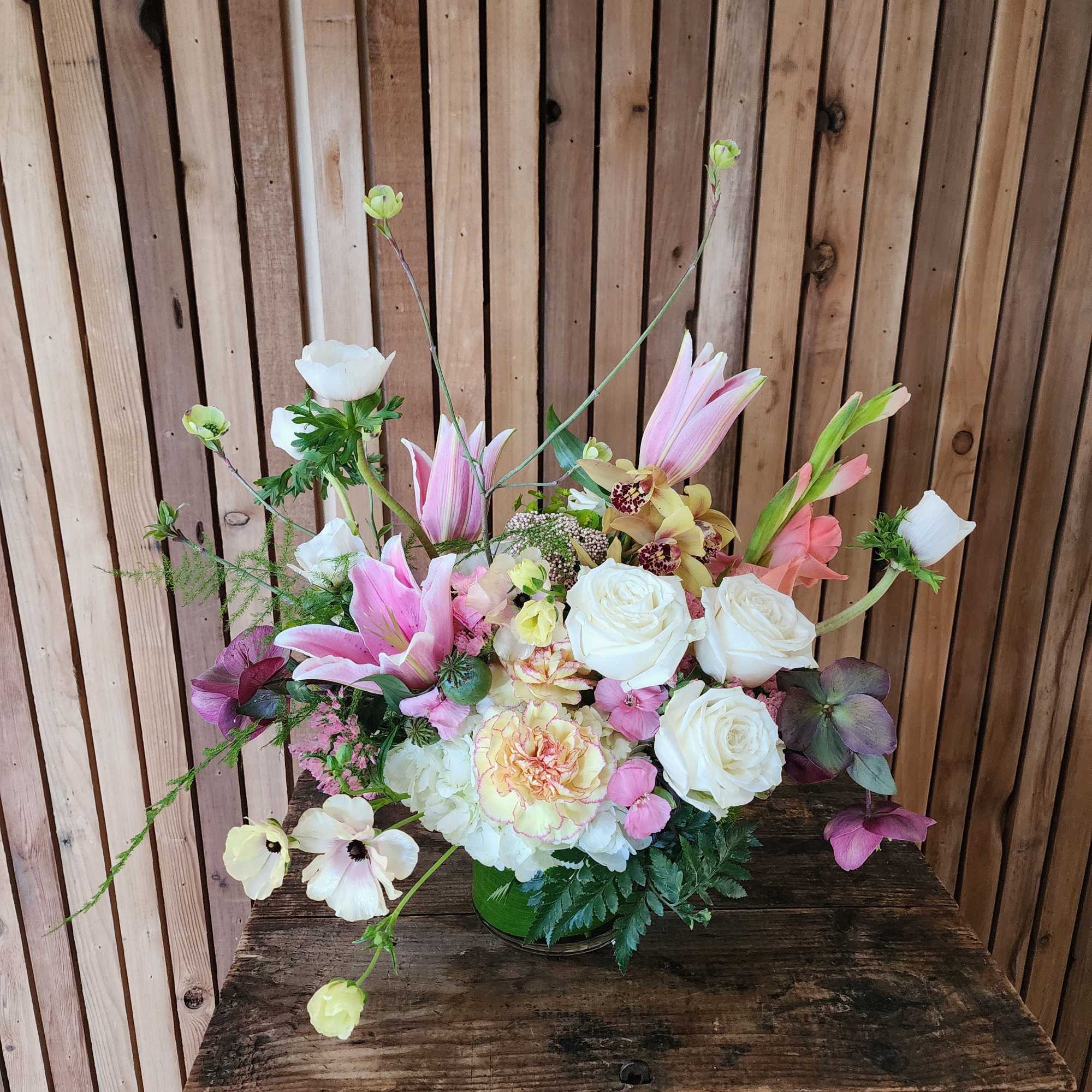 A low, garden-style arrangement in soft seasonal tones of white, pink, and