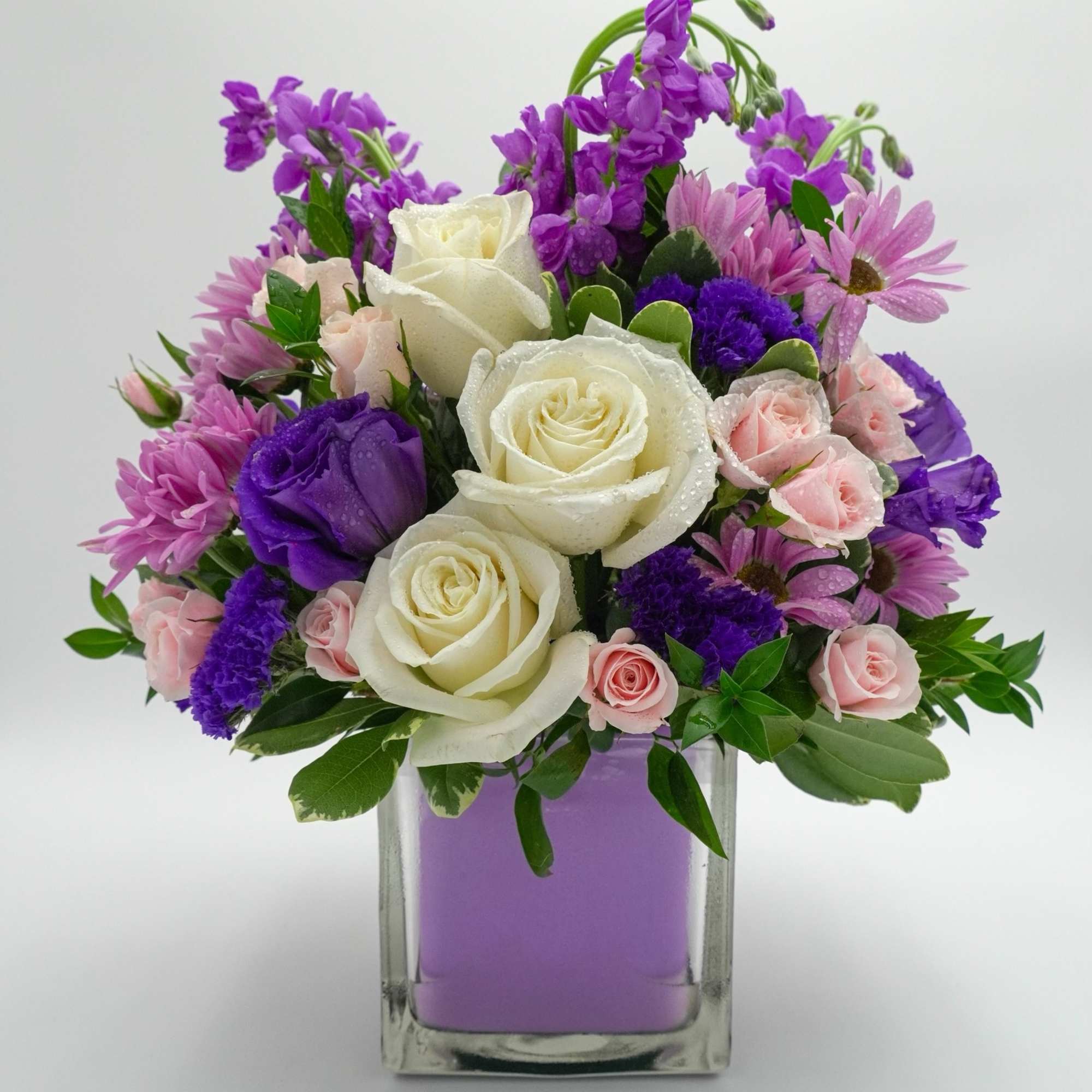 Bouquet of white and pink roses with purple flowers in a glass vase