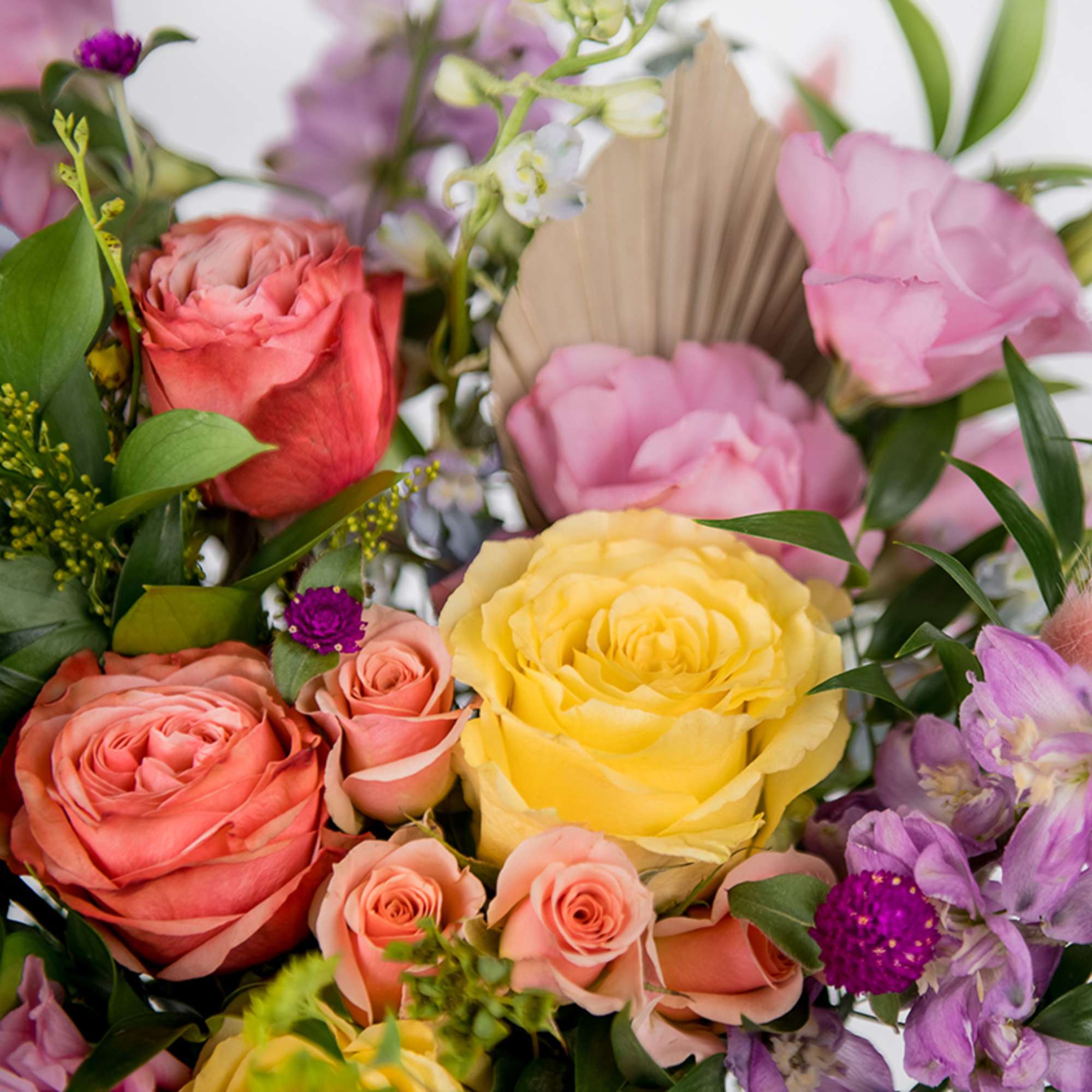 Colorful bouquet with yellow and peach roses, pink blooms, and purple accent flowers