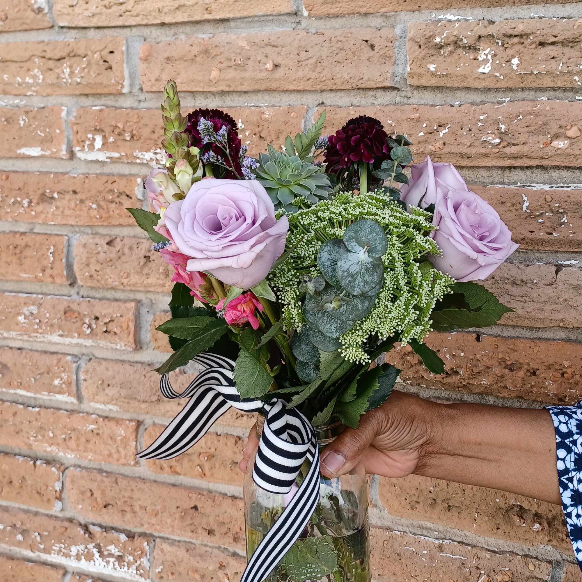 Lavender roses in a glass vase with a striped ribbon