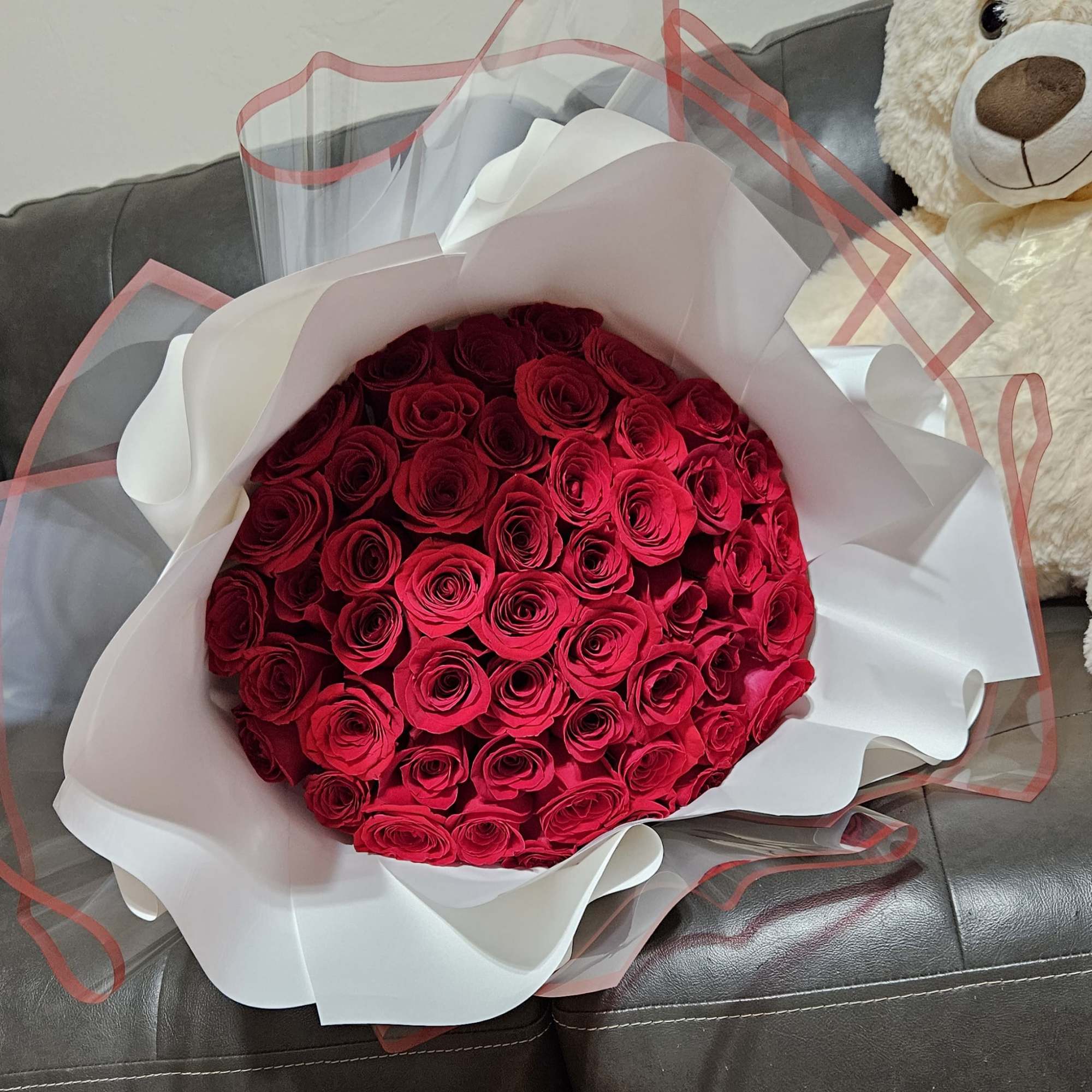 Large bouquet of red roses wrapped in white and pink paper