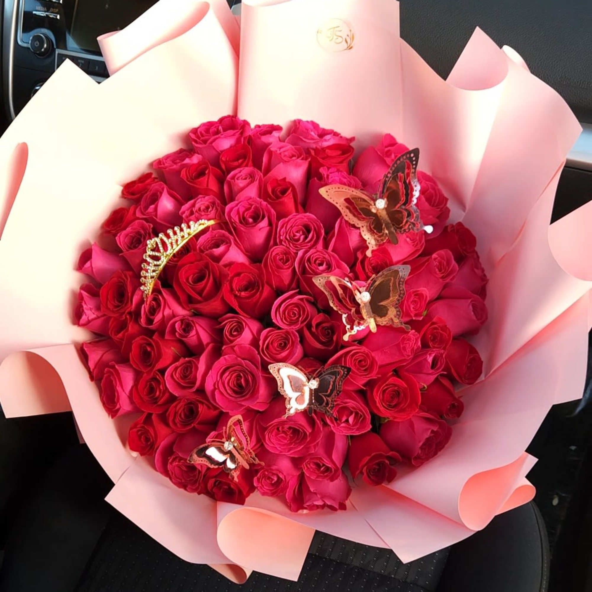 Bouquet of red roses wrapped in pink paper with butterfly picks