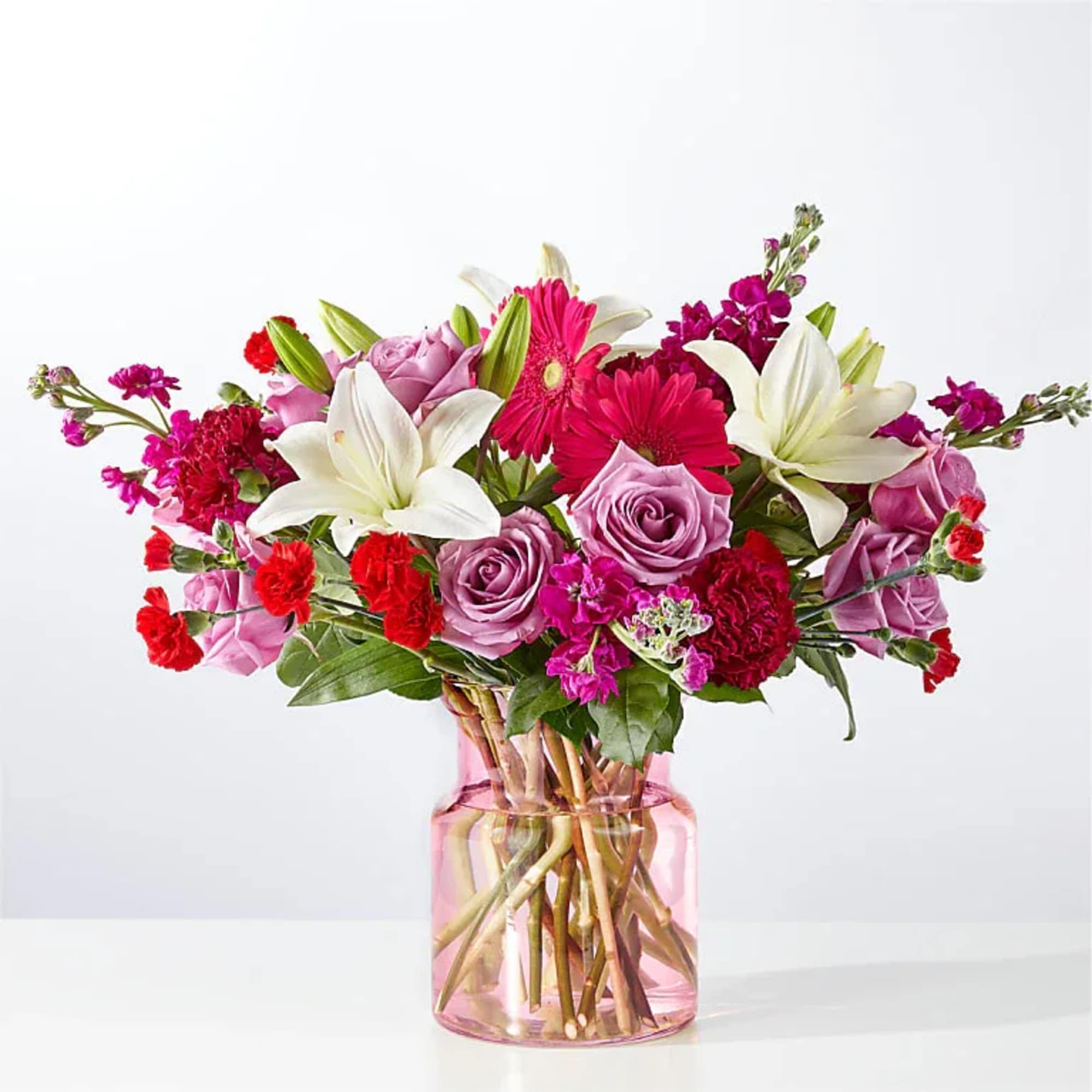 Pink and white mixed flower bouquet in a pink glass vase