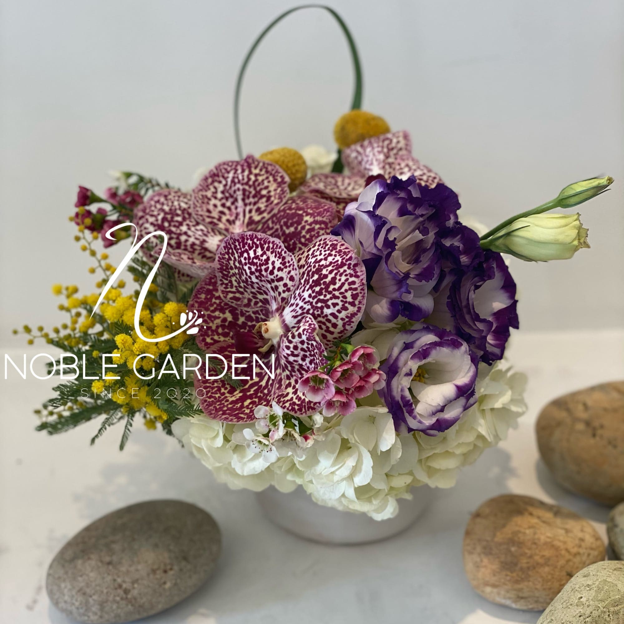 Purple orchids and white hydrangeas in a white basket