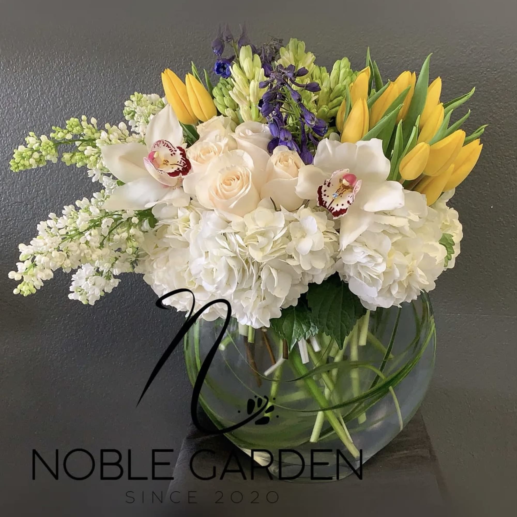 Mixed bouquet of white, yellow, and purple flowers in a glass vase