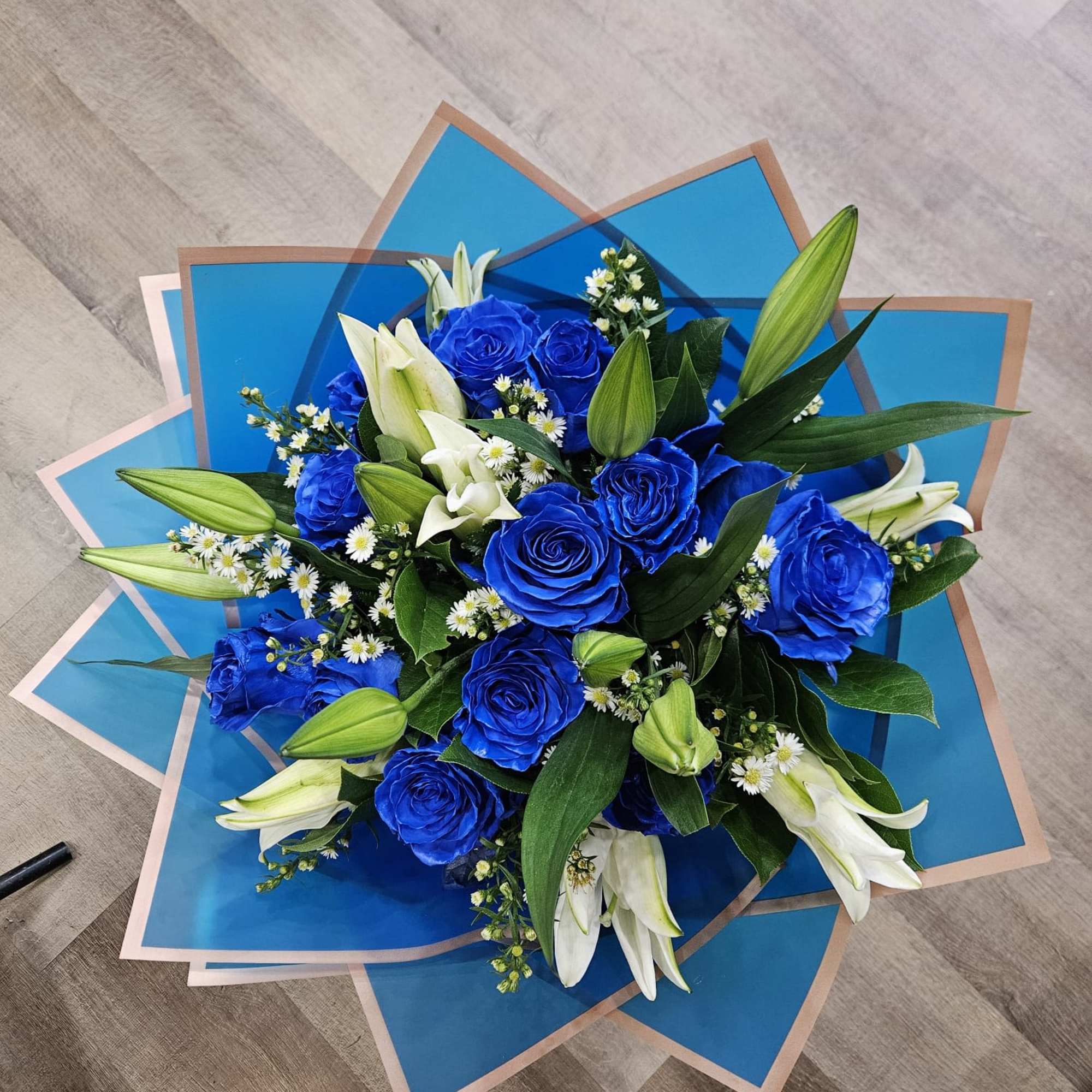 Blue roses and white lilies in a wrapped bouquet