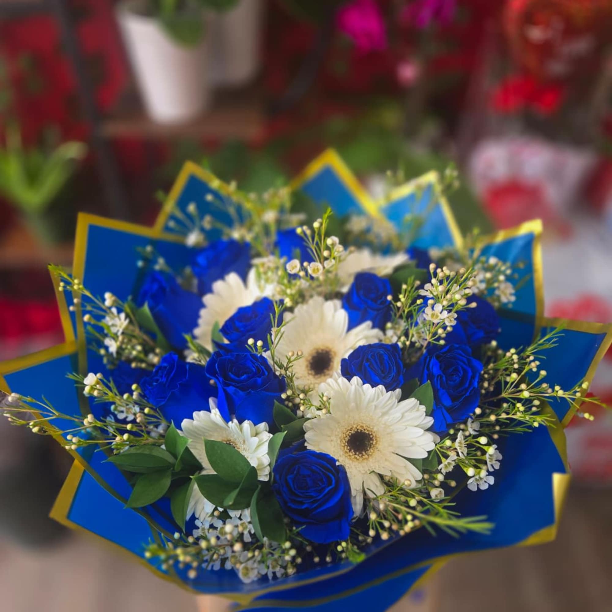 Bouquet of blue roses and white daisies wrapped in blue paper