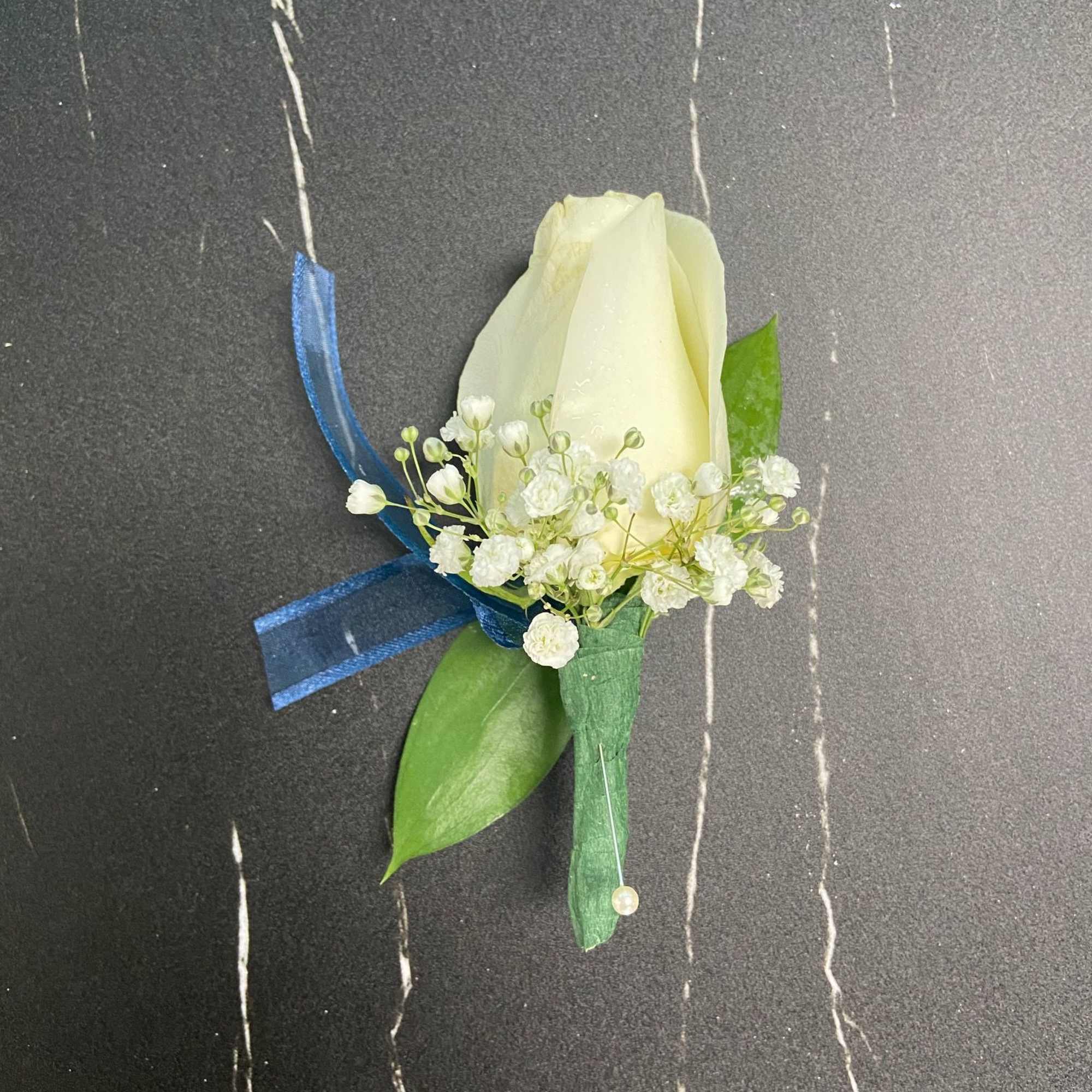 White rose boutonniere with baby's breath and blue ribbon