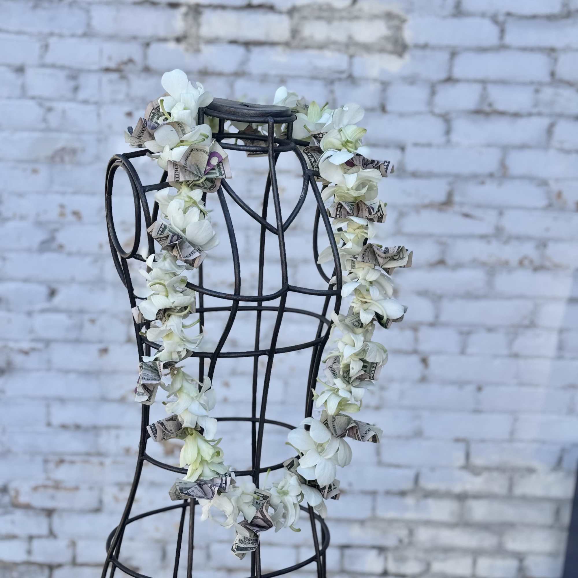 White flower lei draped over a black dress form