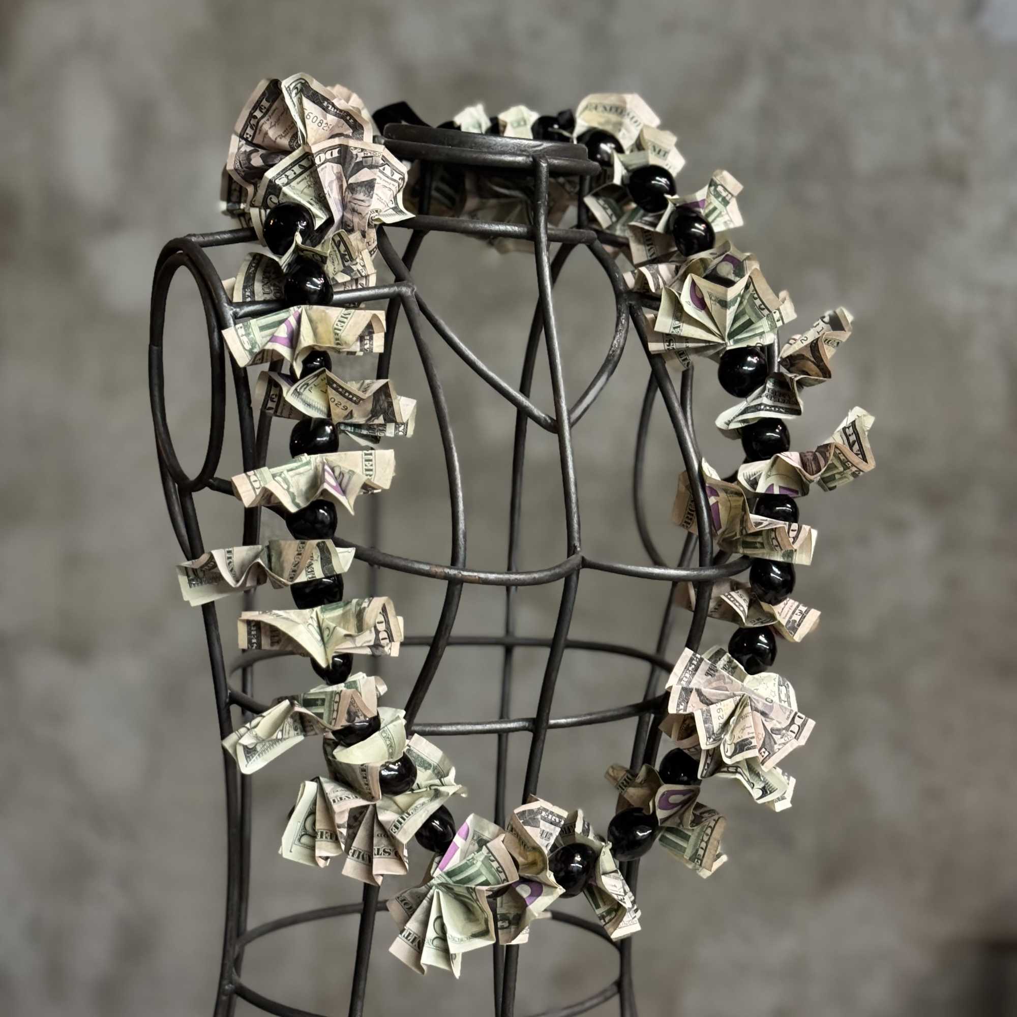 Money lei draped over a black metal dress form