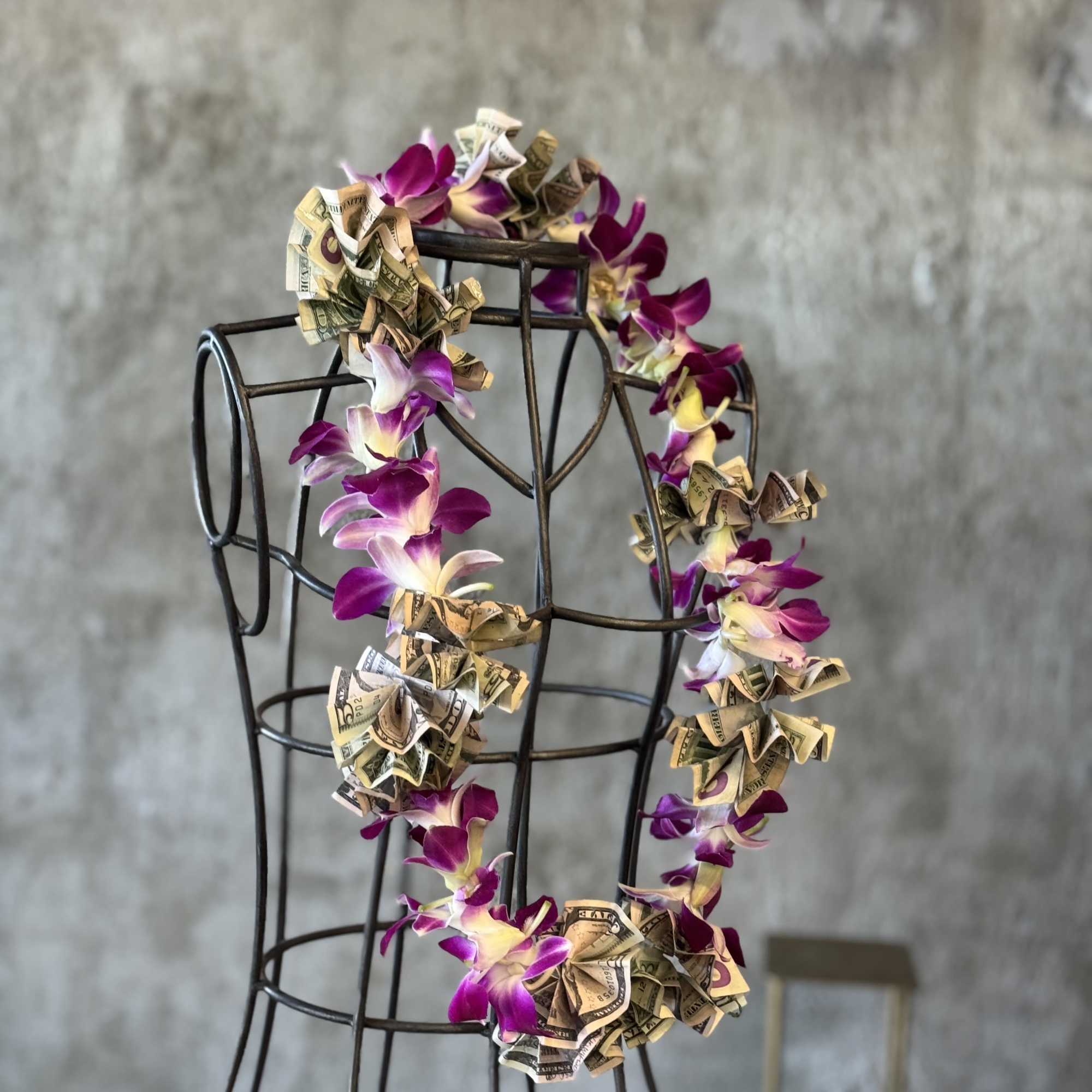 Purple orchid lei draped over a wire dress form