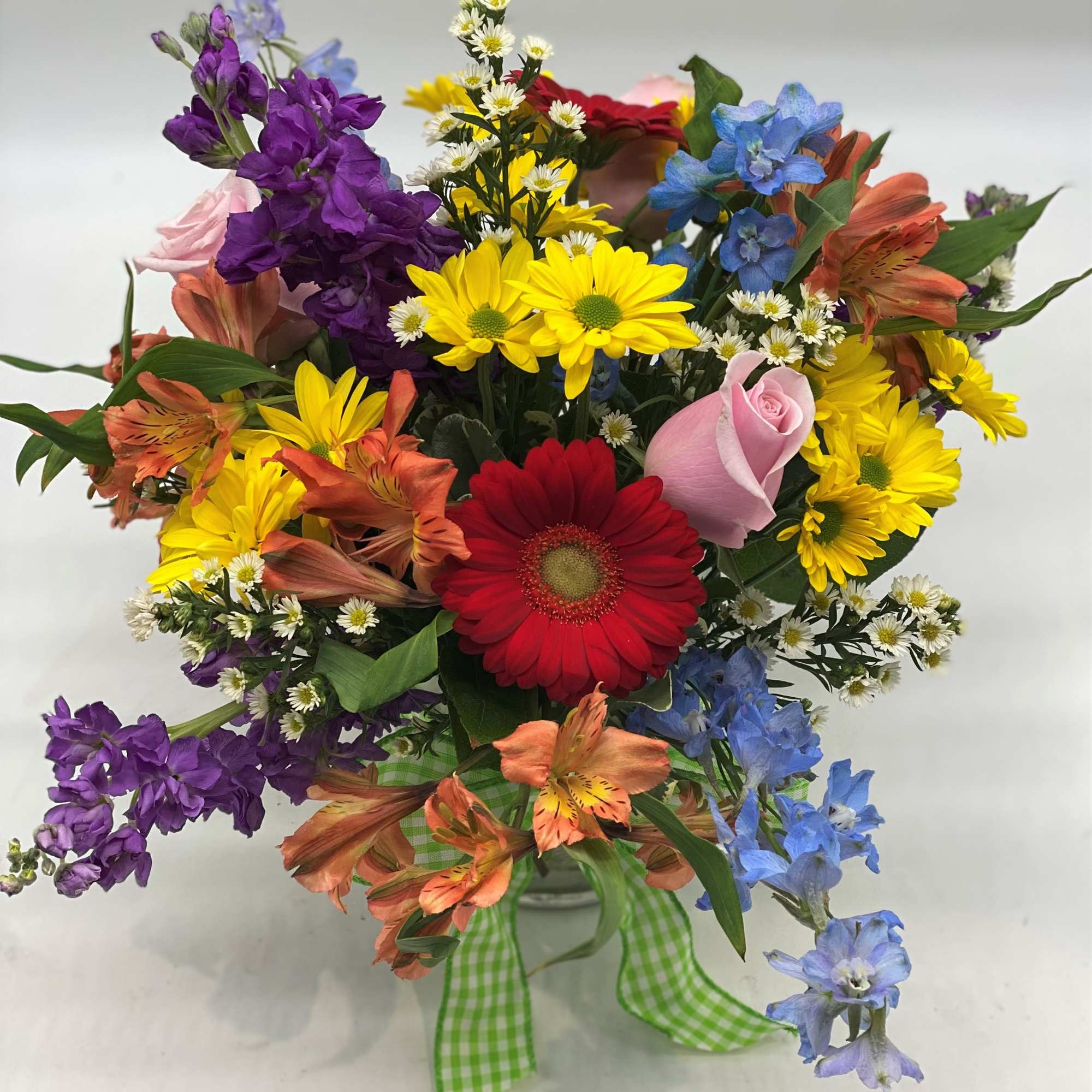 Colorful mixed bouquet with daisies, roses, and alstroemeria in a glass vase