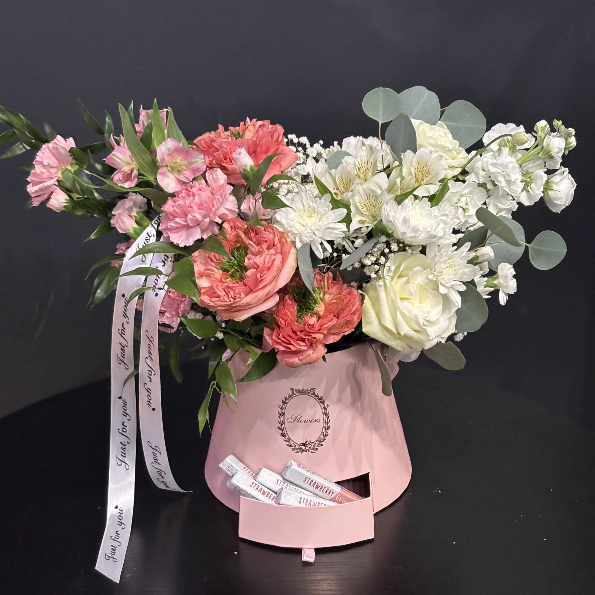 A delicate flower arrangement in a hat box with a pull-out drawer