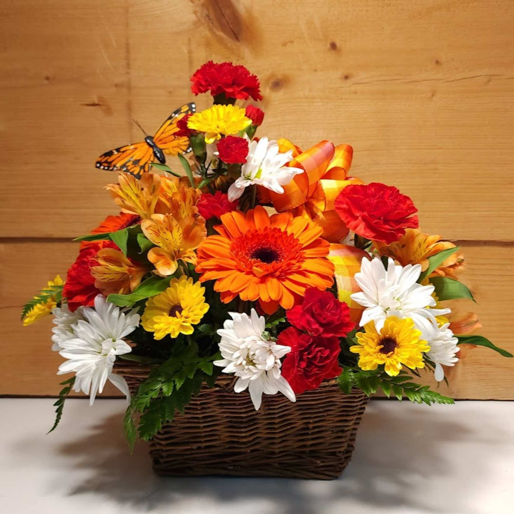 Colorful flower basket with daisies, carnations, and a butterfly decoration
