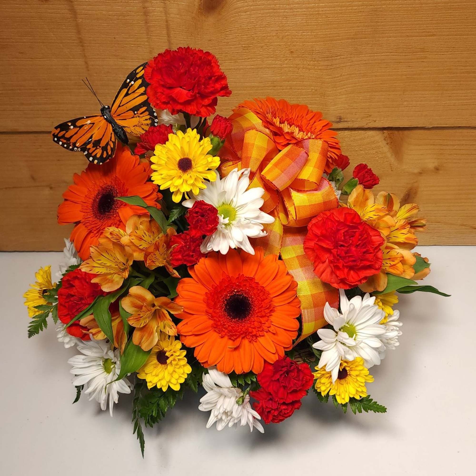 Bright mixed bouquet with gerbera daisies, carnations, and a butterfly accent