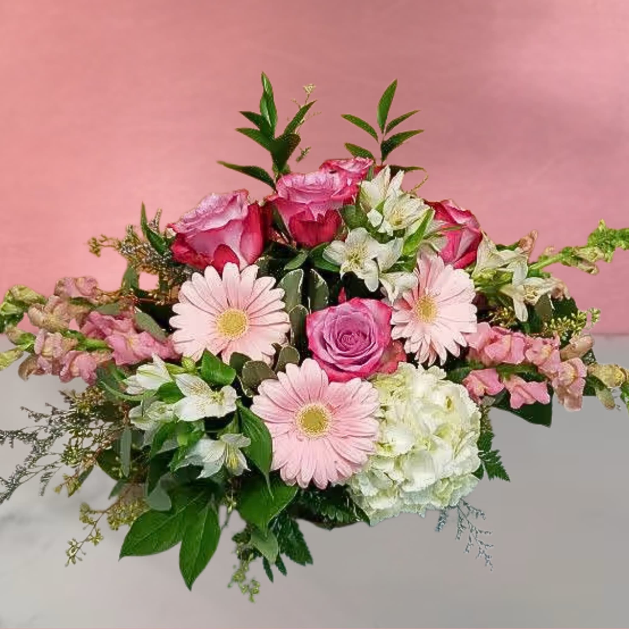 Pink roses and gerbera daisies arranged with white blooms in a bouquet