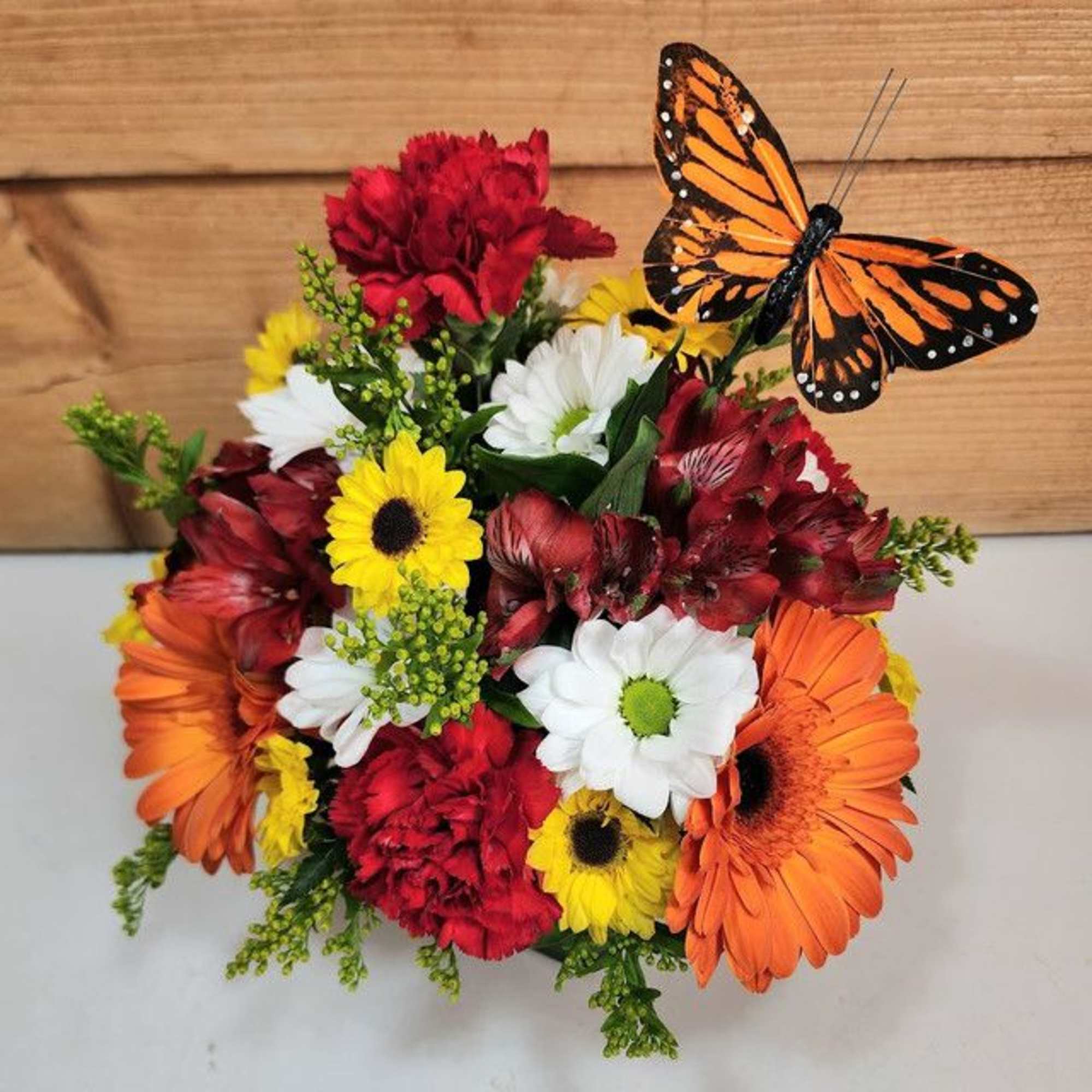 Colorful bouquet of daisies, carnations, and gerbera daisies with a butterfly pick