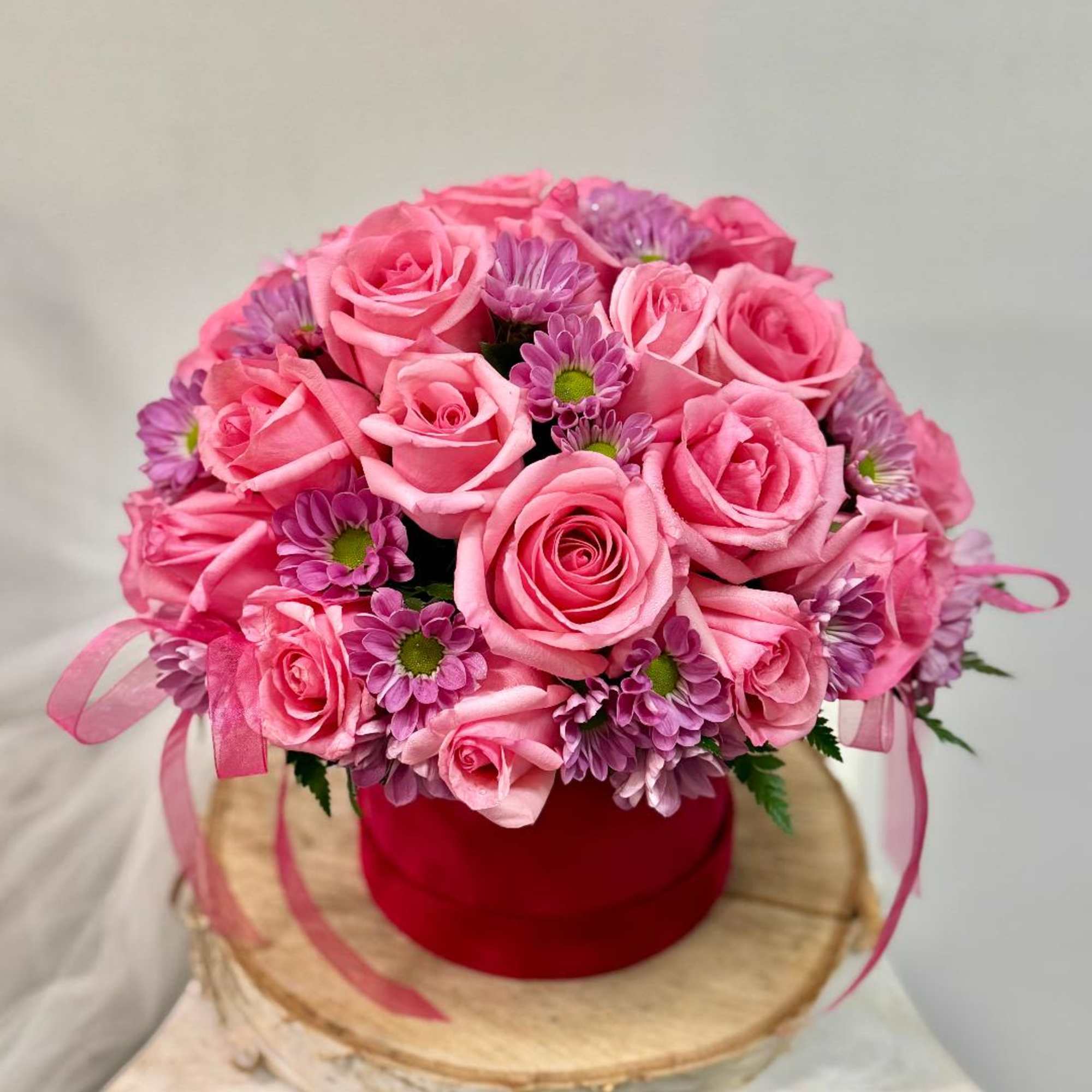 Pink rose and purple daisy bouquet in a red box