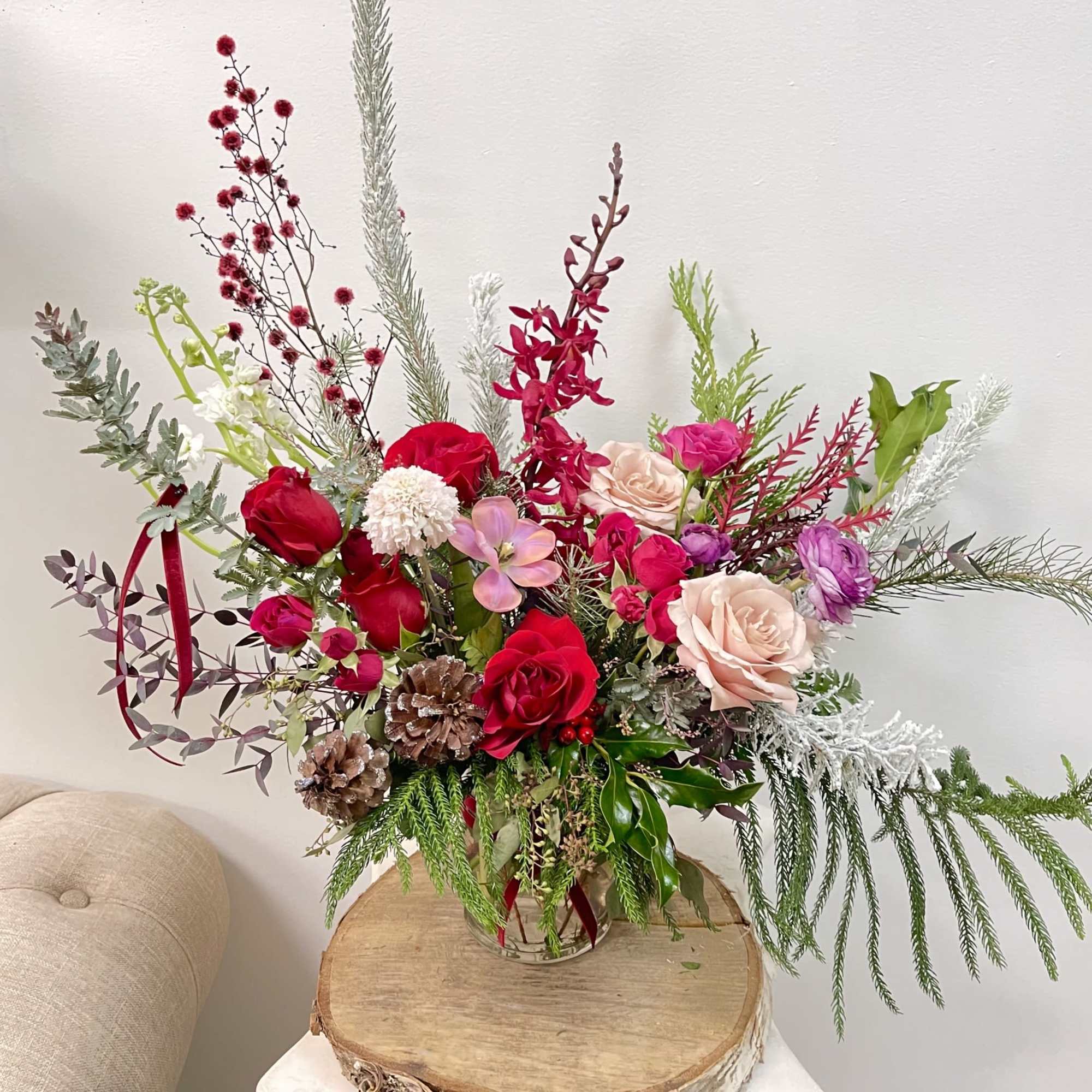 Tall mixed floral arrangement in a glass vase with red, pink, and white blooms