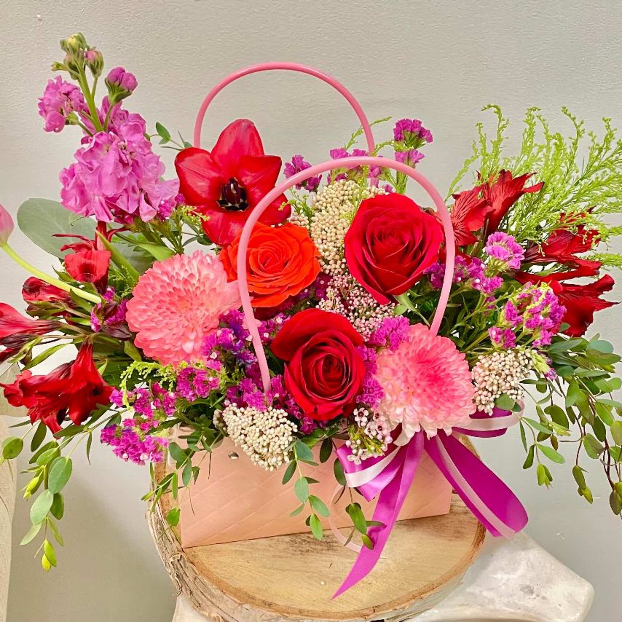 Bright mixed bouquet in a pink handled box with roses and pink blooms