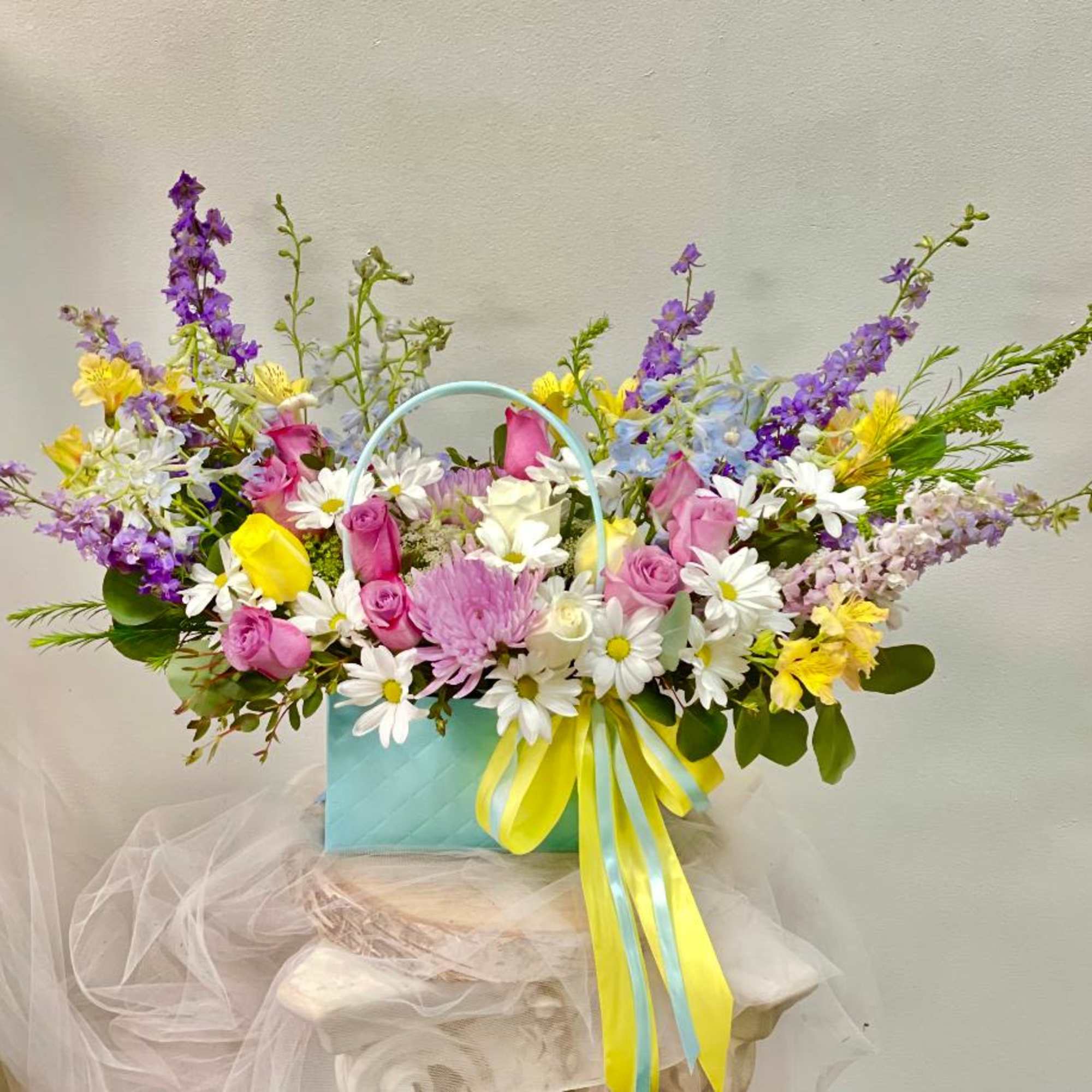 Mixed bouquet in a blue gift bag with pink, white, yellow, and purple flowers