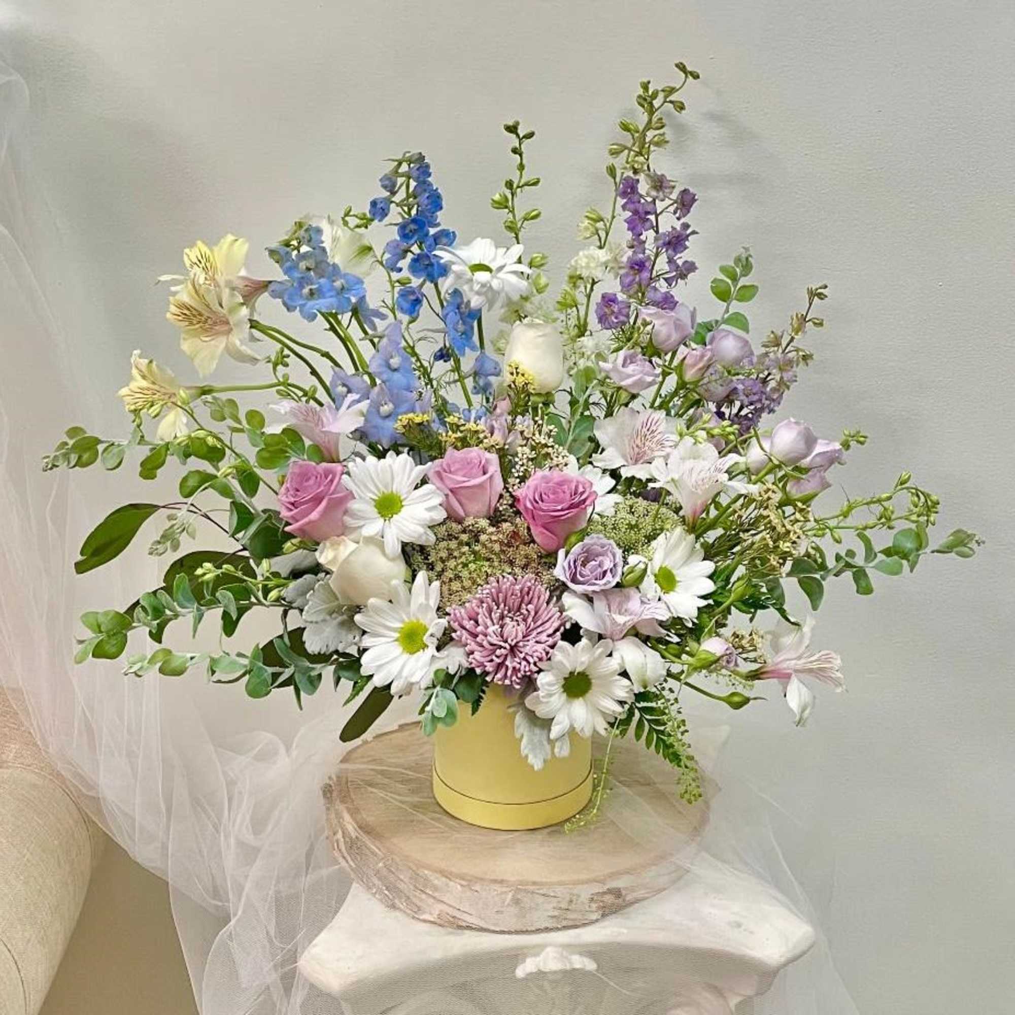 Mixed pastel bouquet in a yellow hatbox with daisies and roses