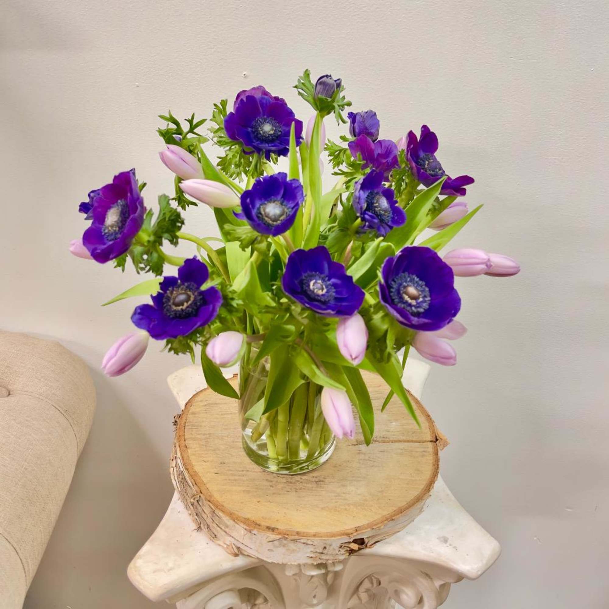 Purple anemones and pale pink tulips in a clear glass vase