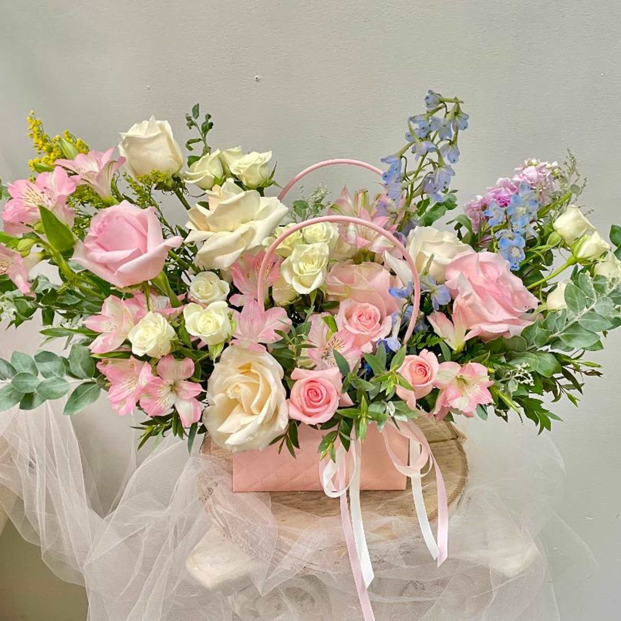 Pink and white rose bouquet in a pink handled box with ribbon